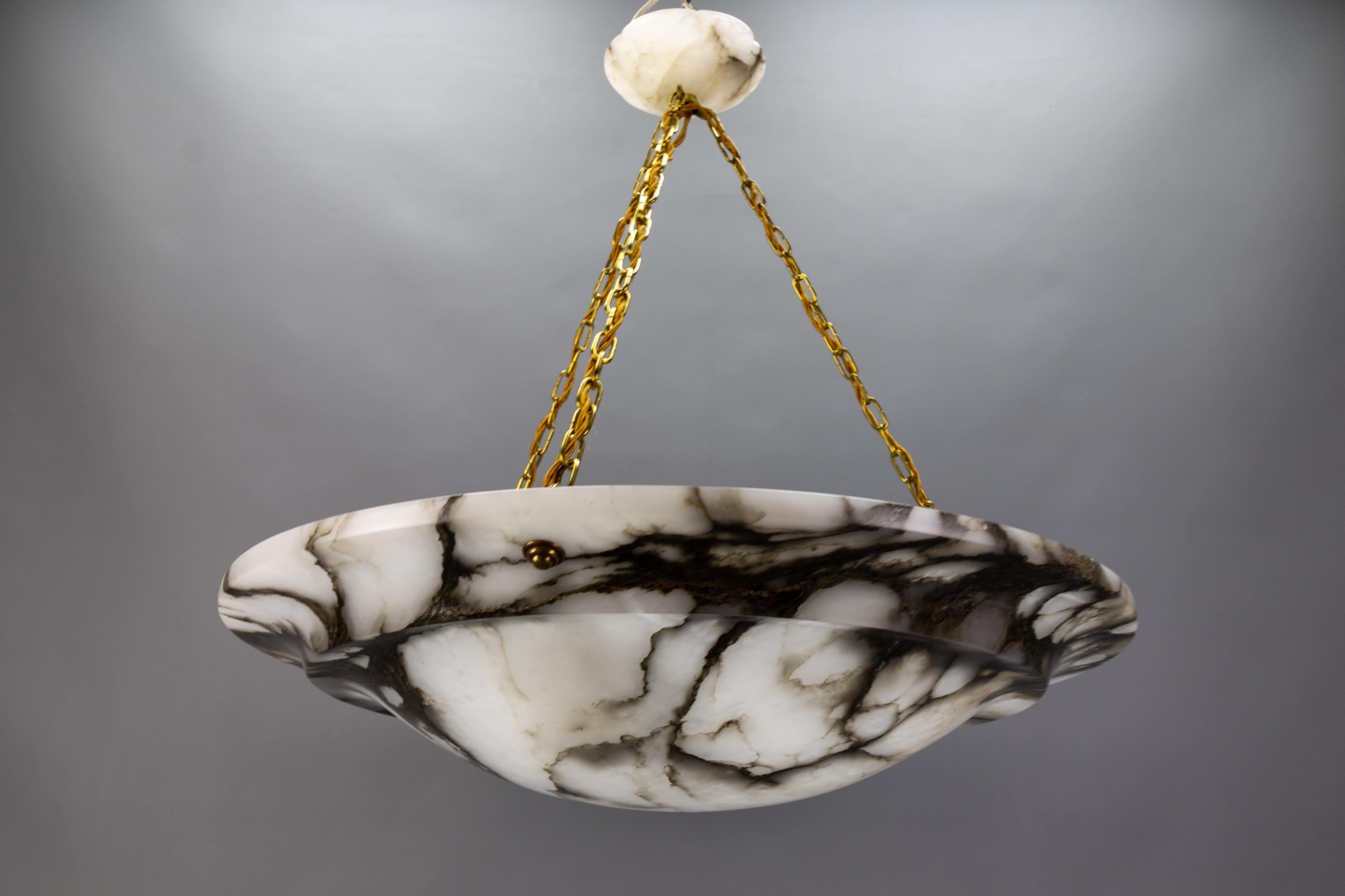 Large black veined white alabaster and brass pendant light fixture, France, circa the 1920s.
An impressive and wonderful alabaster pendant chandelier from circa the 1920s. Beautifully veined and masterfully carved white alabaster bowl suspended by
