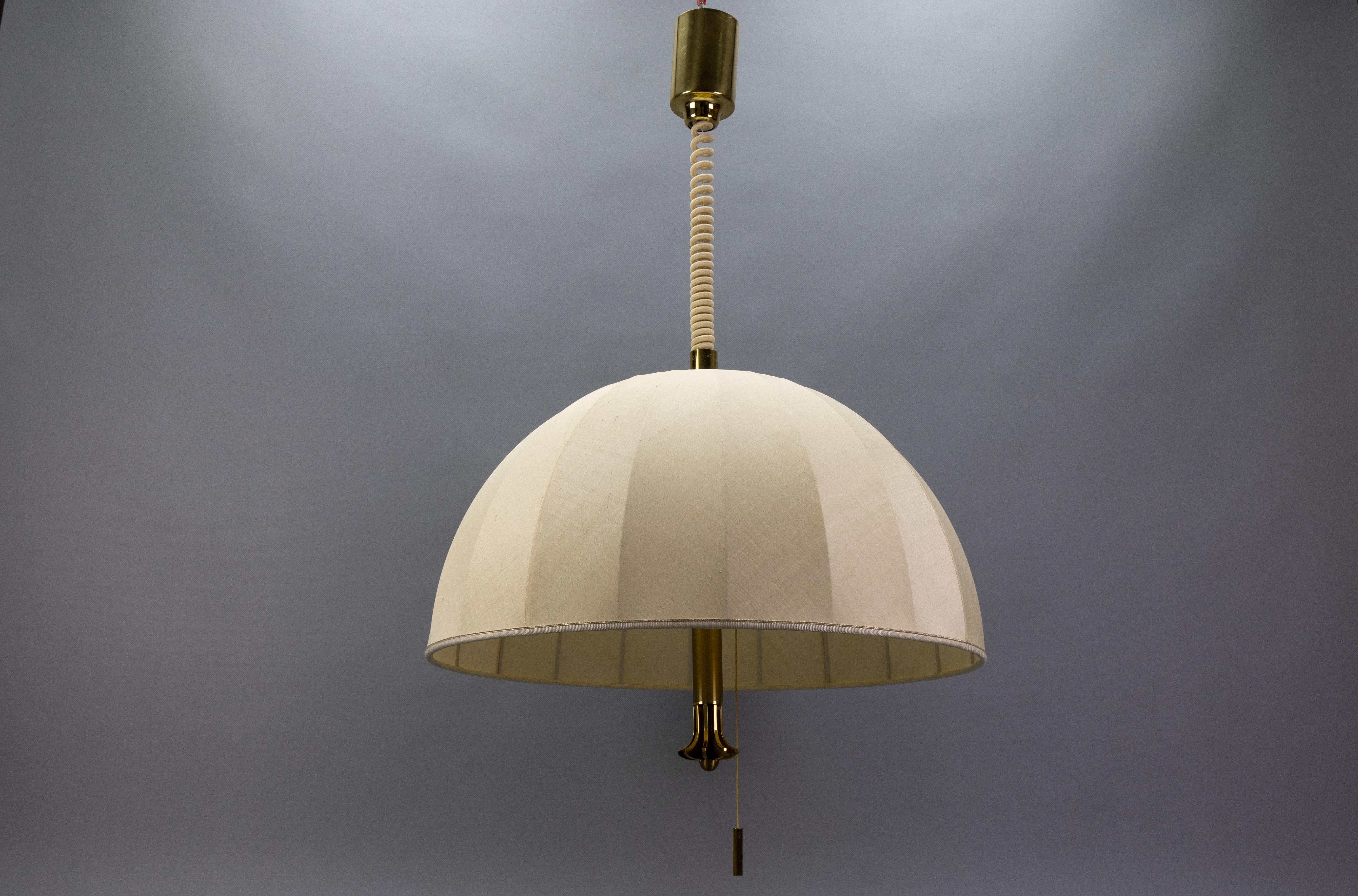 Lampada a sospensione a cinque luci regolabile in altezza in ottone extra large con paralume in tessuto, Germania, circa 1980.
Realizzata in stile The Moderninavian, questa imponente lampada a sospensione presenta un ampio paralume in tessuto