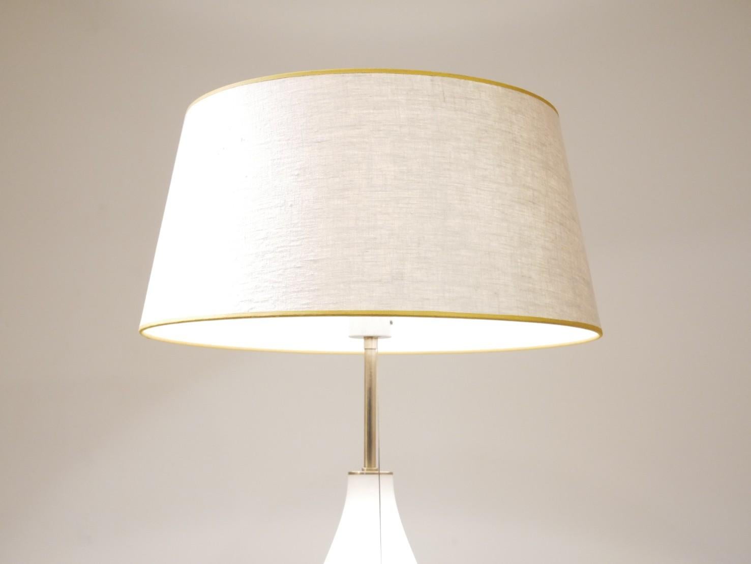 This large table lamp made with curved opalescent glass with a brass base and neck, was manufactured by the German company Peill & Putzler. The lamp shade is made in textile with an embroidered edge that matches the brass elements.