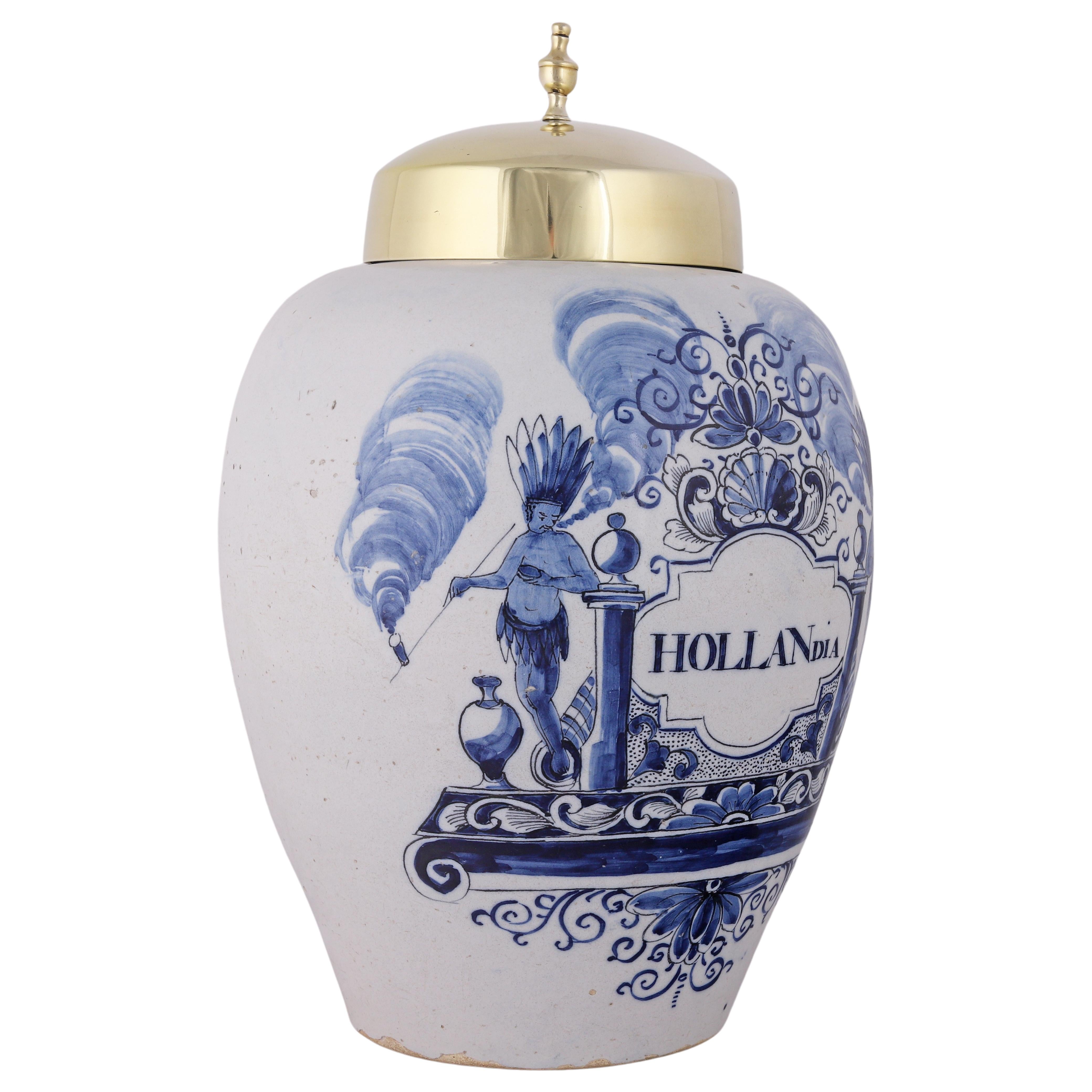Faïence de Delft
1760 - 1790
Atelier inconnu

Un grand pot à tabac bleu et blanc pour le stockage du tabac avec un couvercle en laiton d'origine.
La jarre porte l'inscription Hollandia dans un cartouche orné de motifs floraux et de coquillages. Avec