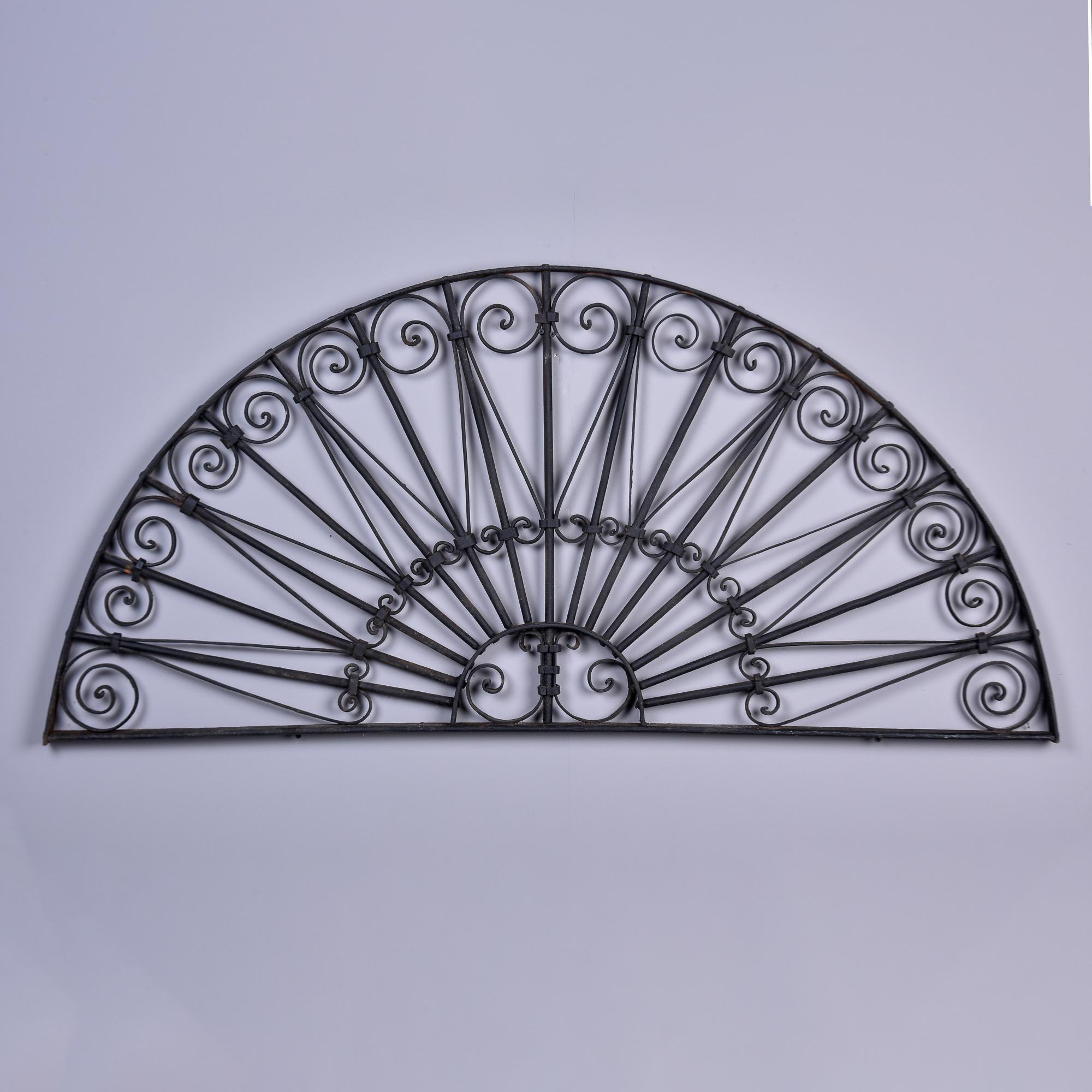Found in the US, this extra large black iron architectural arch dates from the 1930s and is five feet wide. With an open-fan shape, this piece has a sunburst-style center with pointed rays extending out to a border embellished with scrolled iron.