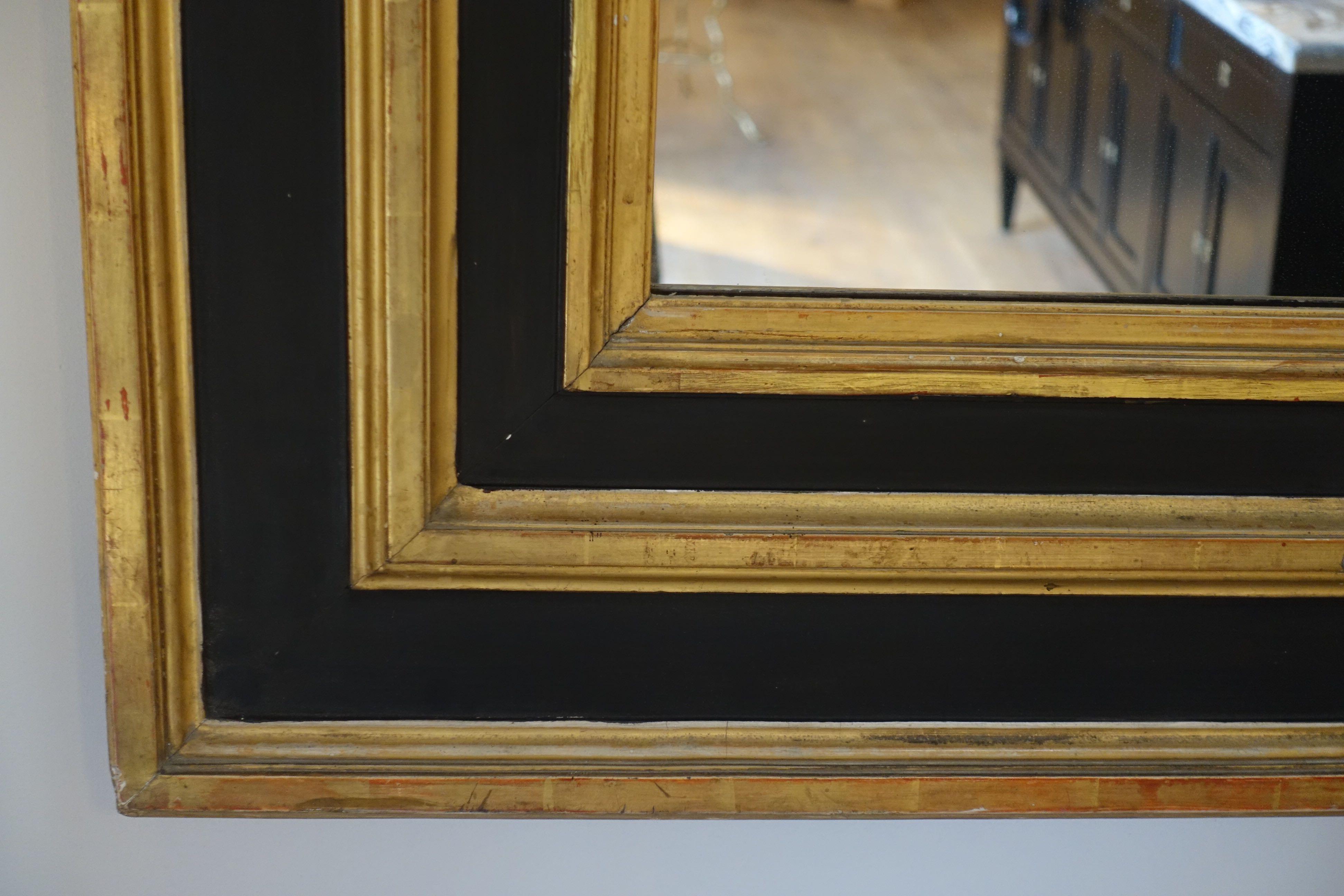 19th century French extra-large mirror with ebonized black wood frame. Three rows of gold gilt accent details emphasize the frame.
Original mercury glass mirror in excellent condition.
   