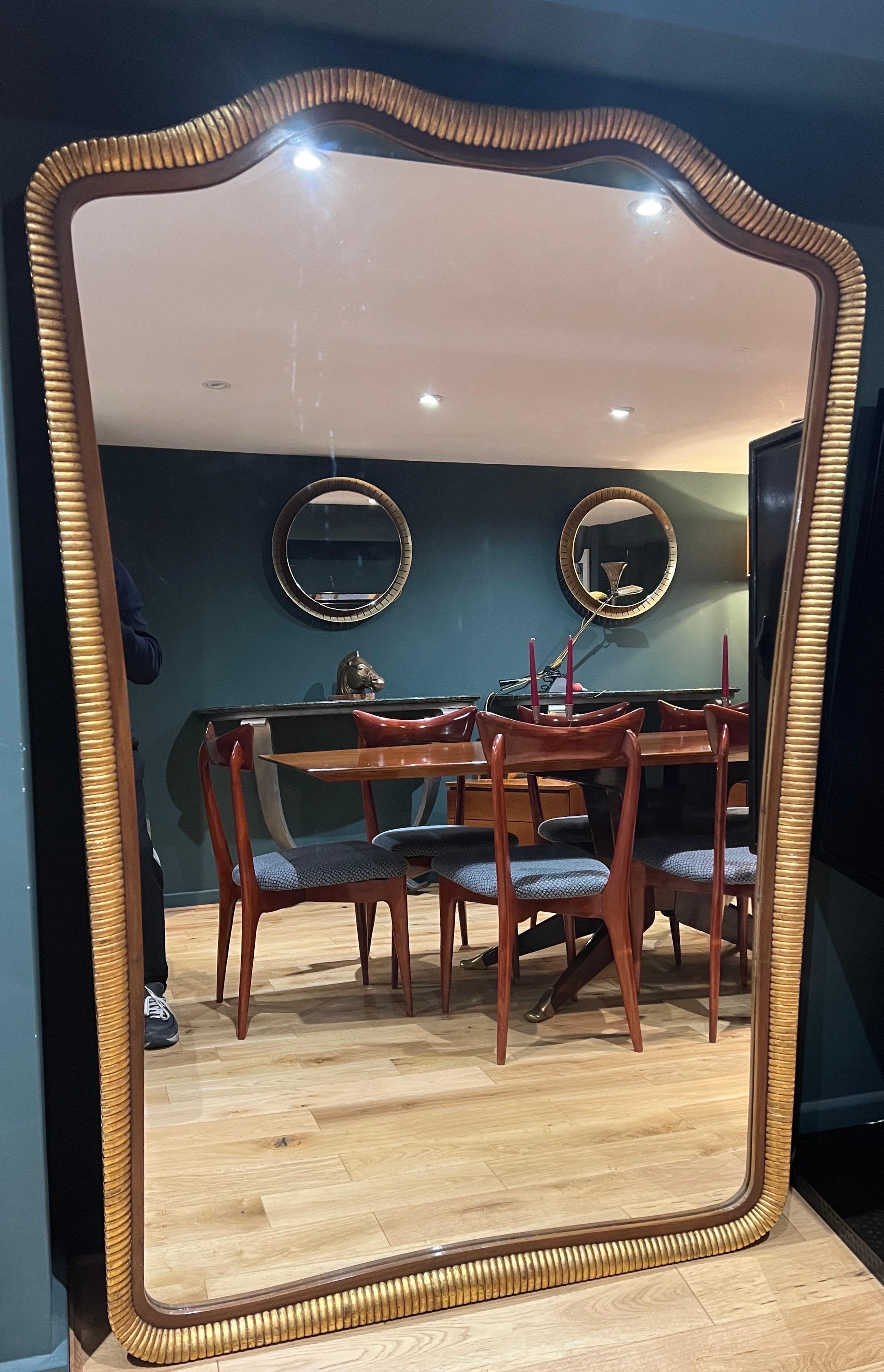 An extraordinary large giltwood mirror beautifully designed with reeded details to the frame in fabulous condition .
A true statement piece for anyone looking for a n alternative to a classical style mirror. 
C1940 
Northern Italy 