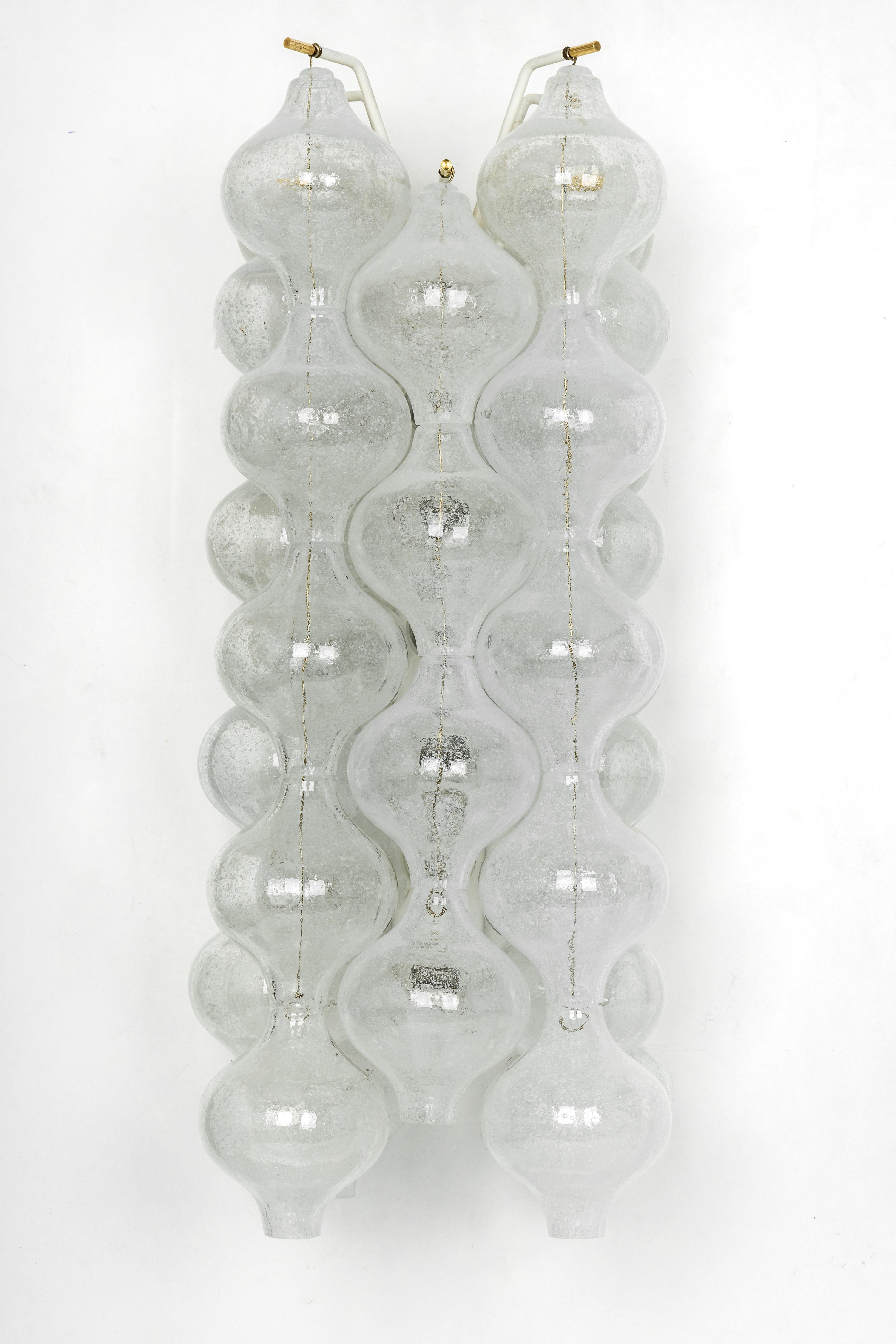 Wunderschöner Wandleuchter aus der Mitte des Jahrhunderts, hergestellt von Kalmar, Österreich, ca. 1970-1979.
Jedes tulpenförmige Glas ist handgefertigt, was jedes Glas zu einem Einzelstück macht. Die Leuchte besteht aus 32 Glasstücken auf einem