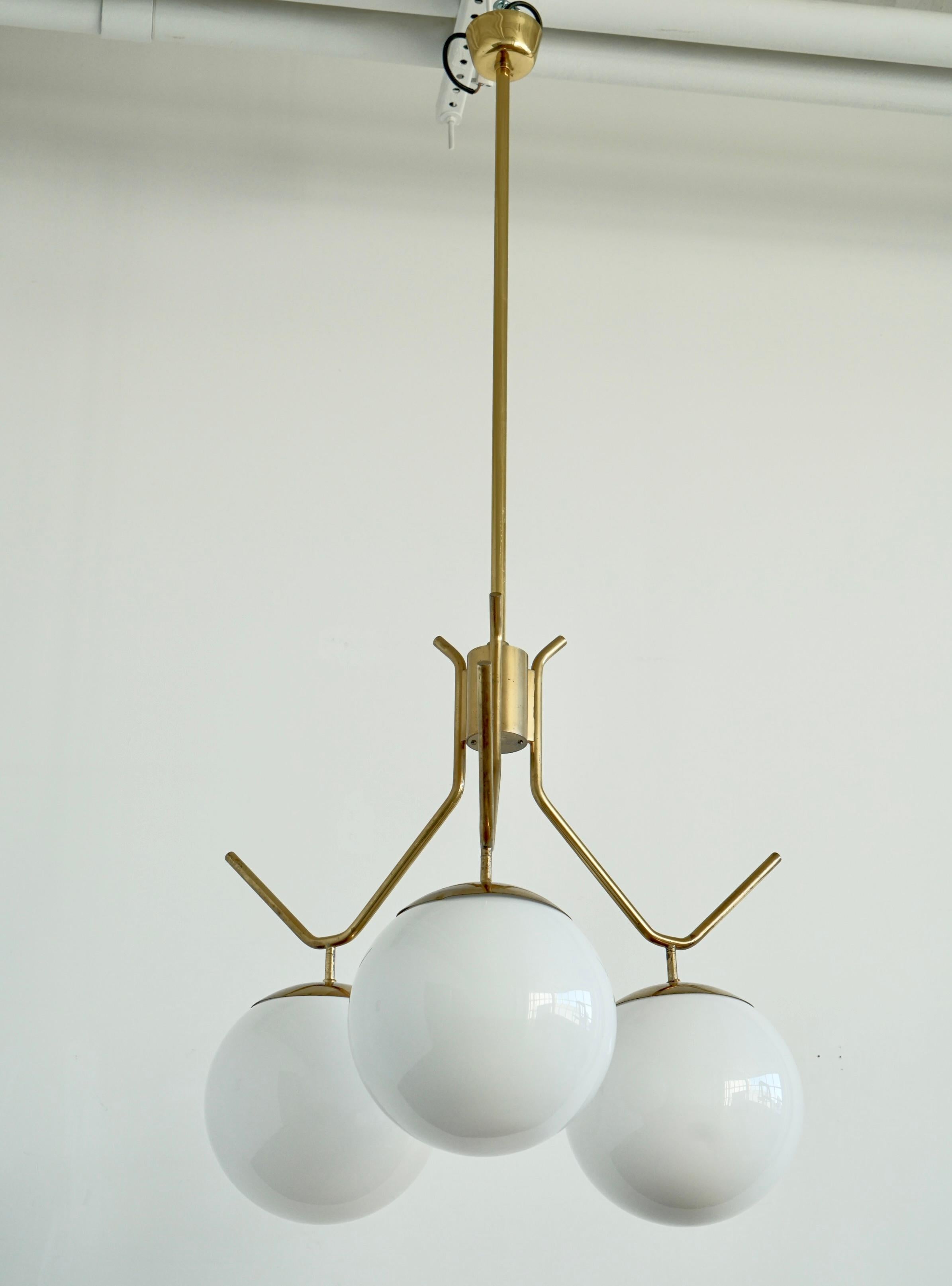 Colgante de iluminación extragrande diseñado por Paavo Tynell para Idman Oy, Finlandia, hacia 1950. Tulipas de cristal opalino en forma de bola sobre herrajes de latón pulido.
Con el sello 