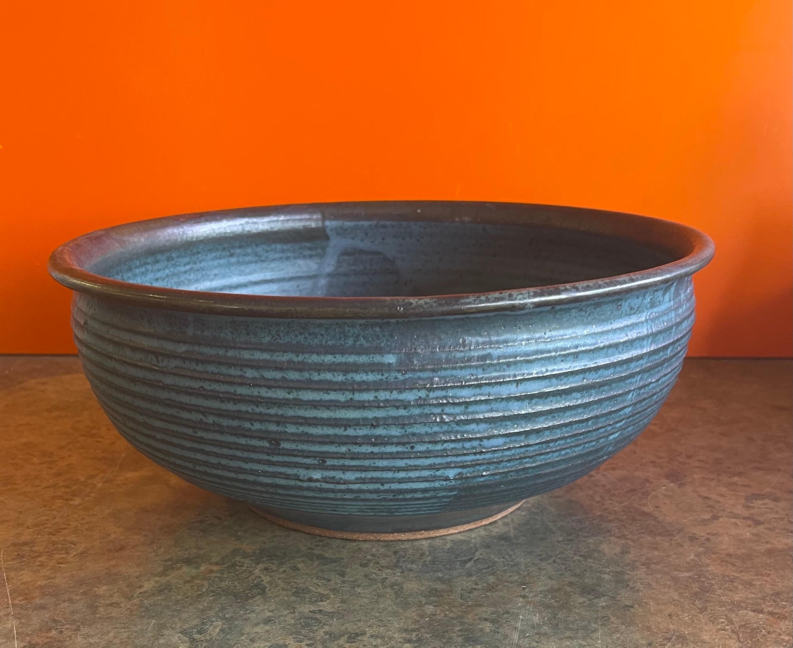 Extra large mesa blue stoneware studio pottery bowl by William Wyman, circa 1965. This studio art piece is quite rare and difficult to find. This gorgeous wheel thrown and hand finished bowl has a wonderful concentric design and vibrant blue colors.