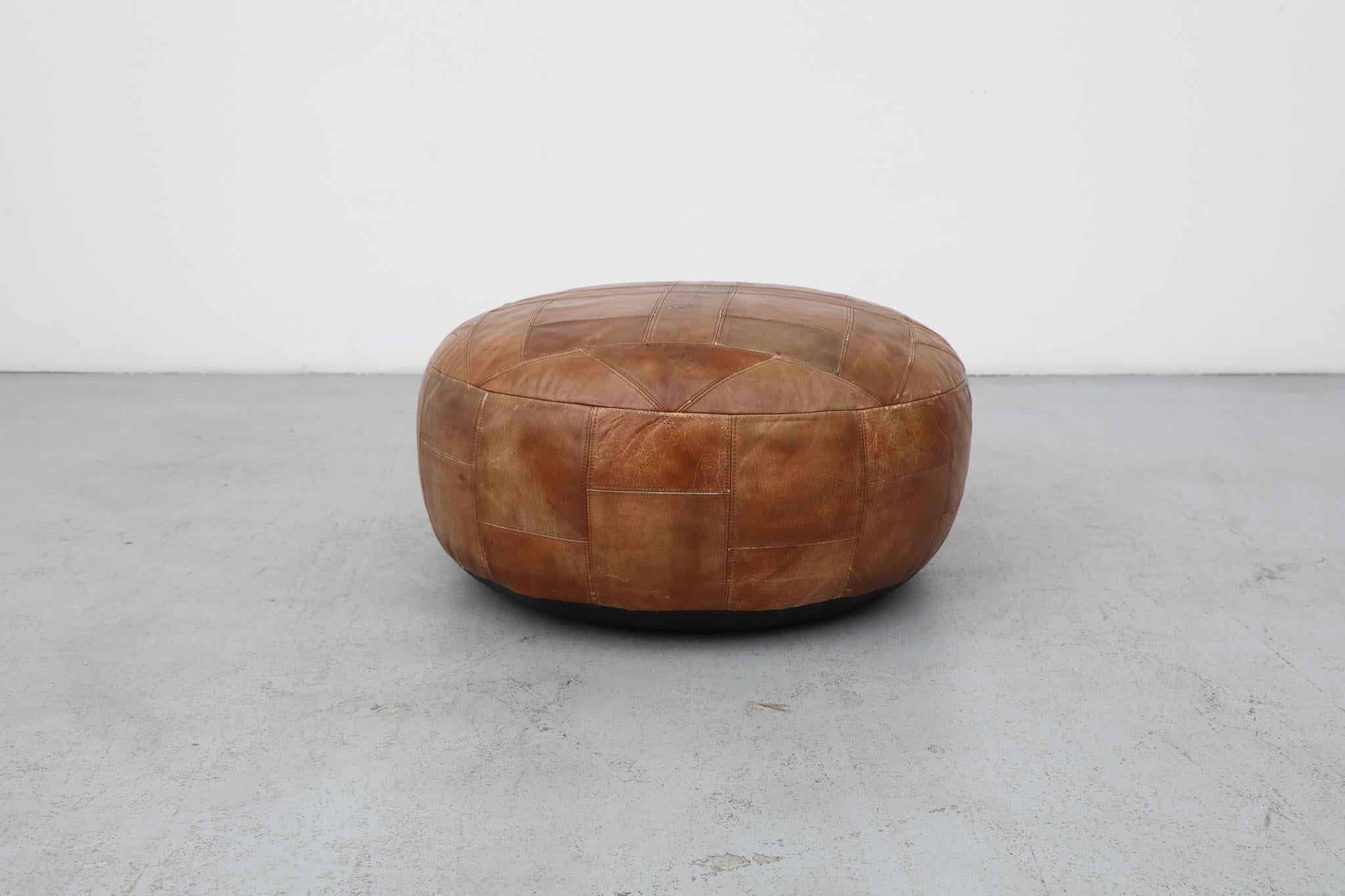 Mid-Century natural leather patchwork ottoman in the style of Dutch manufacturer De Sede. A dense and attractive ottoman that doubles as a comfortable seat or a stylish accent piece. This piece is in original condition with some visible age