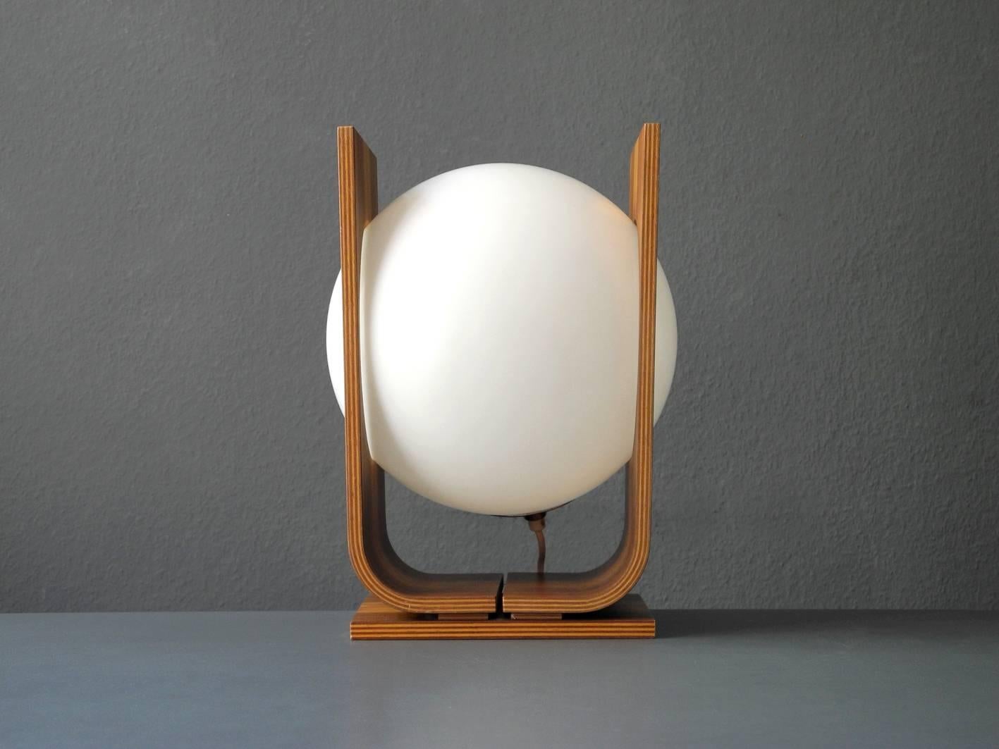 Gorgeous original 1960s table lamp from the German-Swiss lamp manufacturer Temde. The frame is made of bent plywood, outside with walnut veneer, and with a shade of white plastic in the middle in the shape of a globe. Very high quality. 100%
