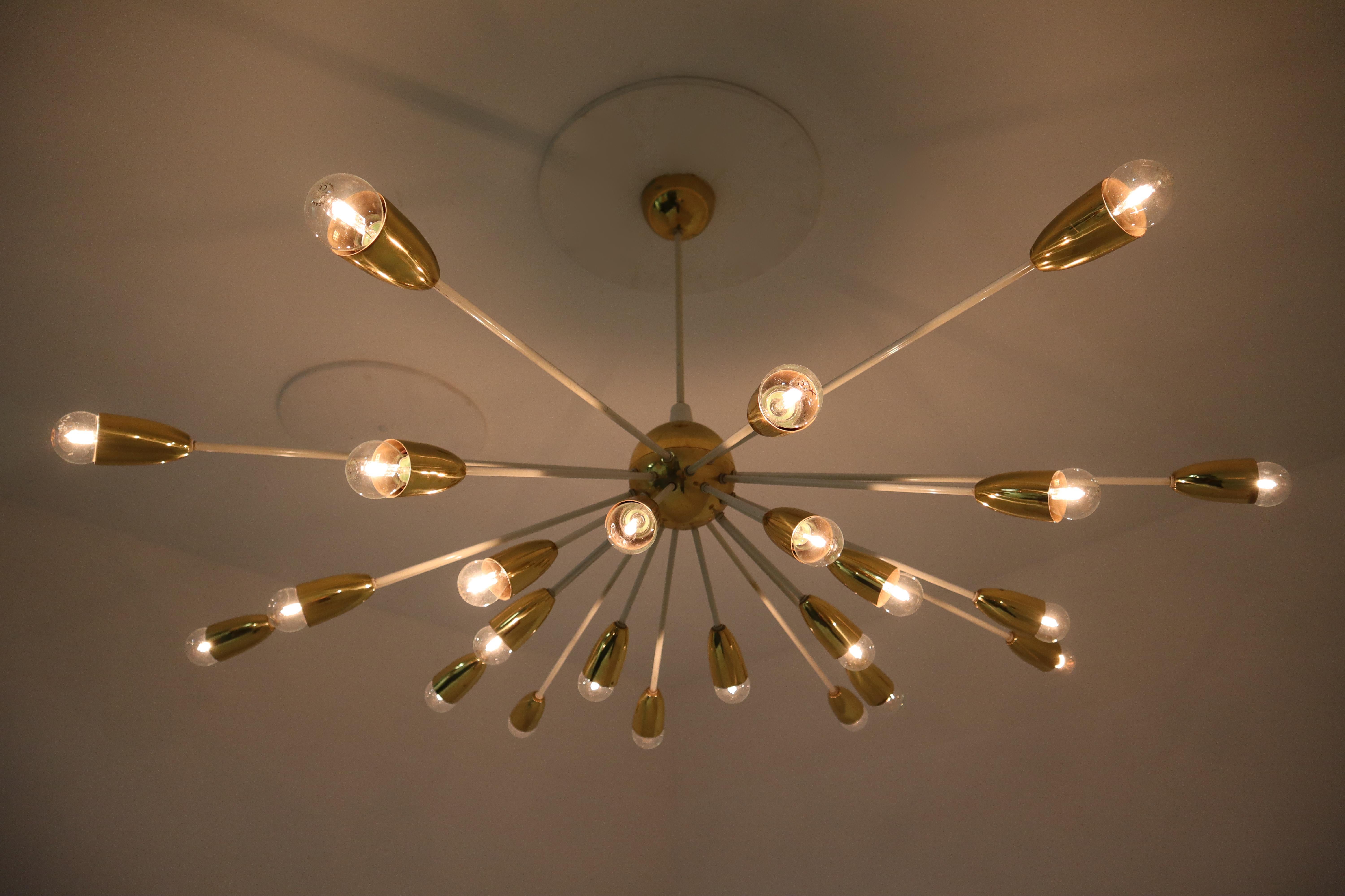 Five unique large Mid-Century Modernist Sputnik features a sculptural form design on a patinated white coated brass frame with 24 brass lights. These large chandeliers with brass frame consist of 24 lights, formed in a circle. The pleasant light