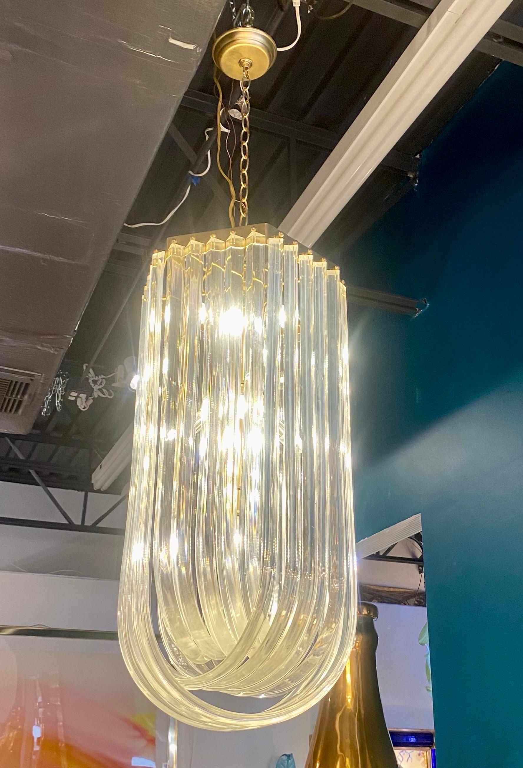 Un delizioso lampadario a nastro in lucite con struttura in ottone. Nastri scultorei di lucite intrecciati pendono dalla struttura in ottone in strati intrecciati, circa anni Settanta. La lunghezza della caduta dal baldacchino alla base del