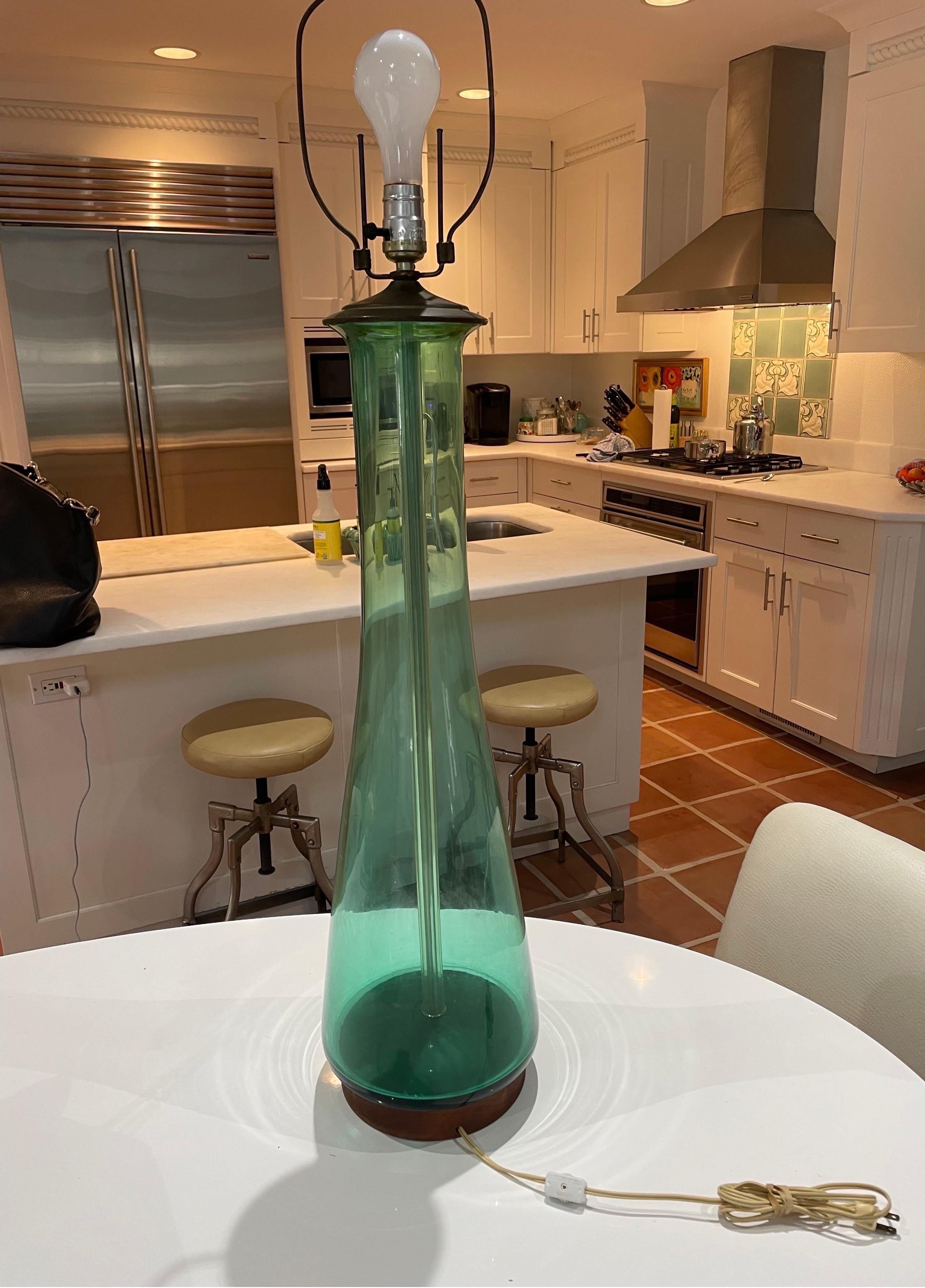 Voici une superbe lampe de table en verre turquoise du milieu du siècle dernier. Il est doté d'une base en bois brun et d'un capuchon en laiton terni. Matériel d'origine 