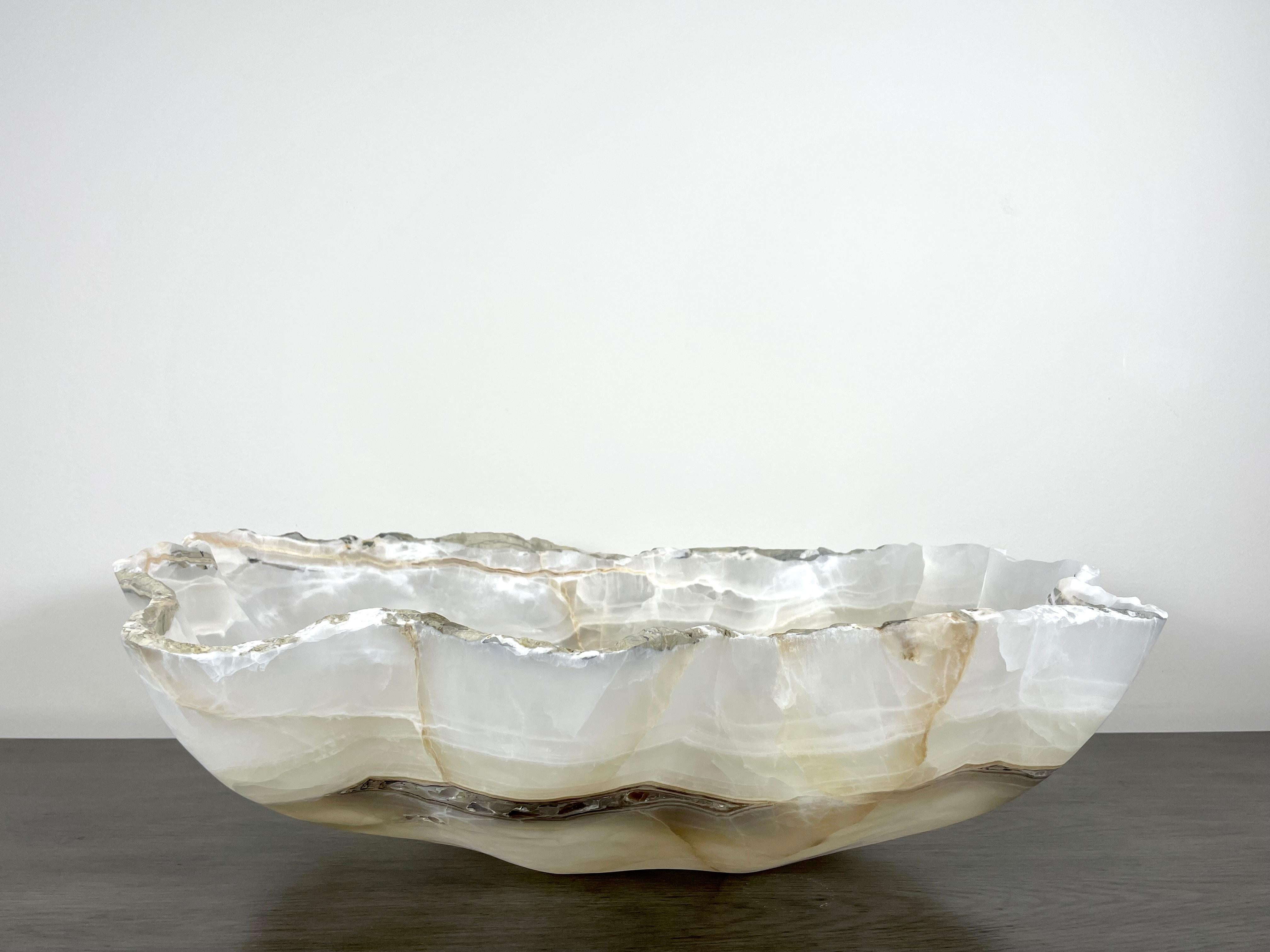 A stunning extra large white onyx bowl with accents of pale grey, greige and black/brown. This one of a kind decorative bowl is meticulously hand-carved from a single piece of onyx by skilled artists to reveal its' inherent characteristics such as