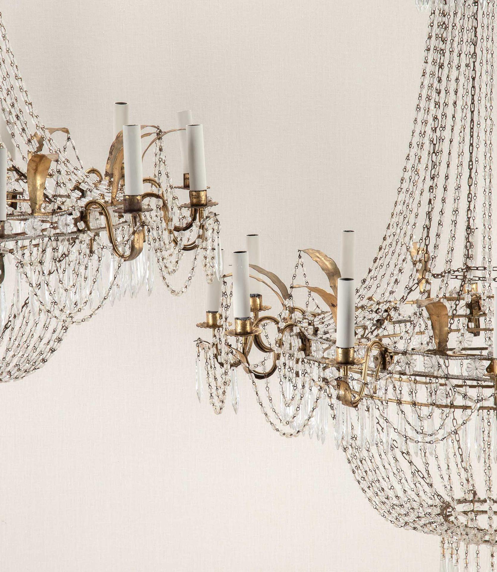 Large pair of early 20th Century Italian twelve arm chandeliers. 
With wrought gilt metal frames and crystal drops. Circa 1920.
Newly rewired to UK standards with new candle fittings.