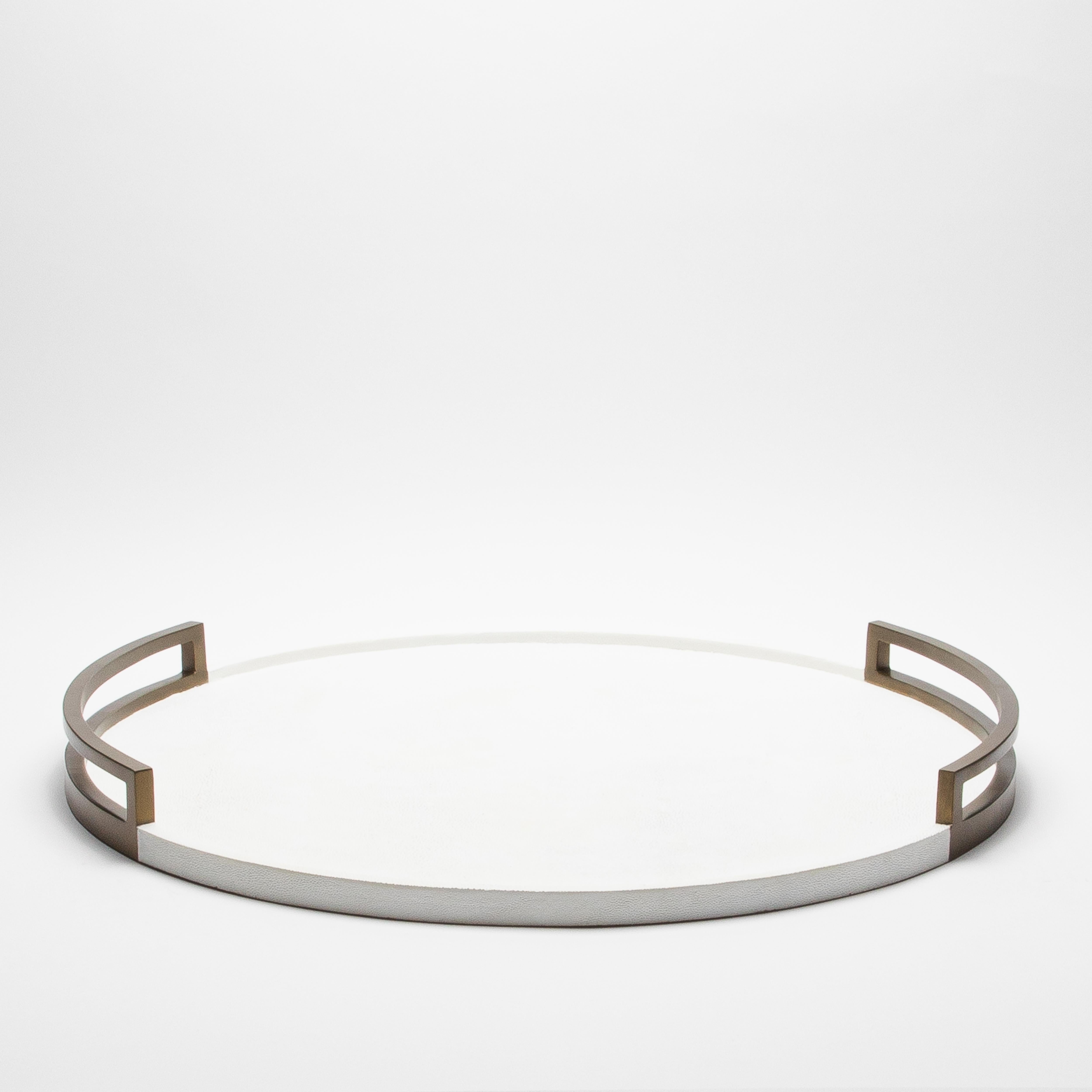 Le plateau rond Extra Large de R&Y Augousti respire l'élégance avec sa luxueuse surface en galuchat blanc, savamment encadrée de laiton patiné bronze. Ce plateau fabriqué à la main, avec ses lignes épurées et ses poignées distinctives, trouve un