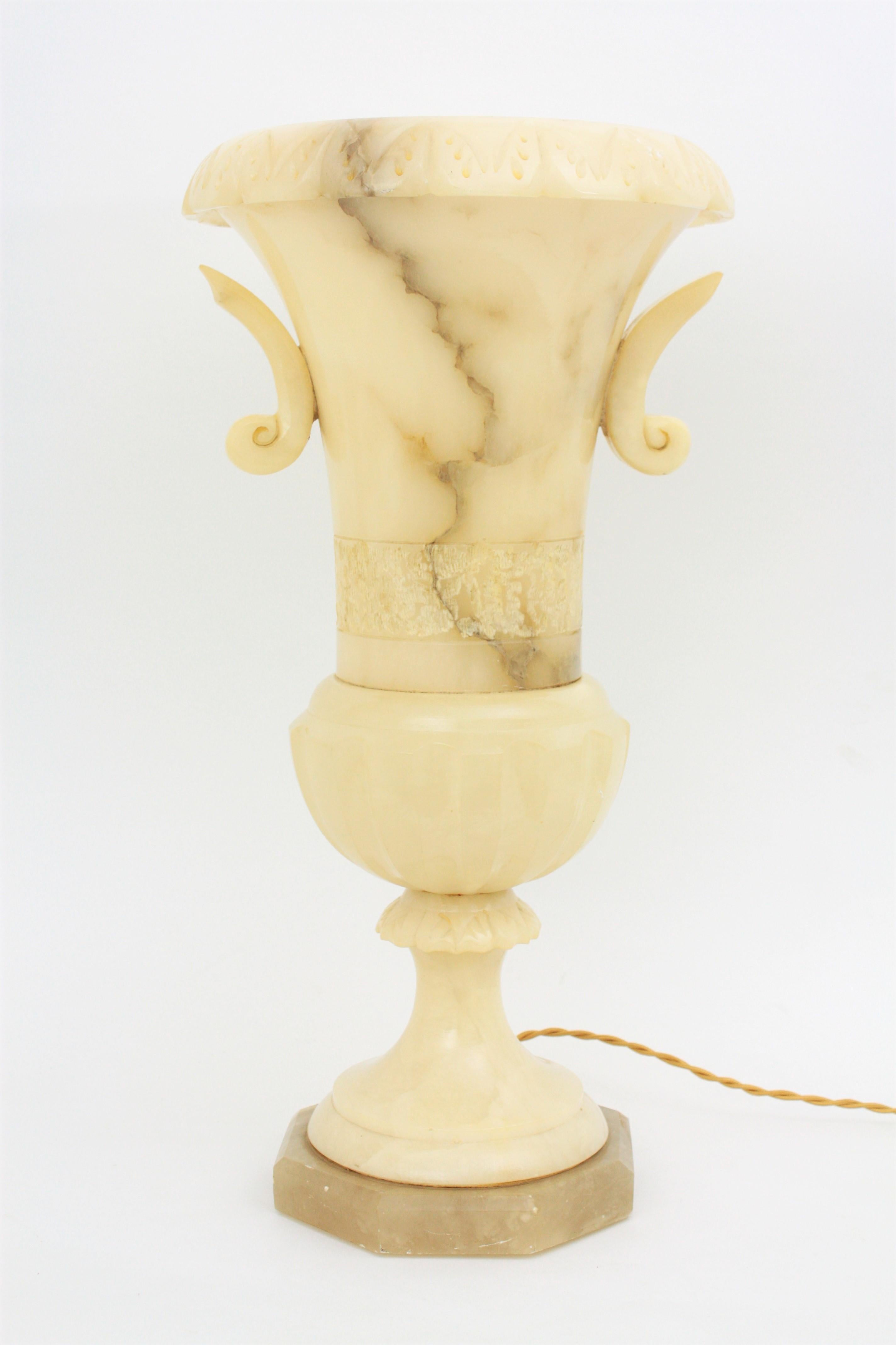 Sculptural large scale carved alabaster Art Deco period urn lamp with neoclassical design flanked by curved handles. Spain, 1930s.
It has carved decorations on the top, a decorative pattern surrounding the body, a magnificent color and an excellent
