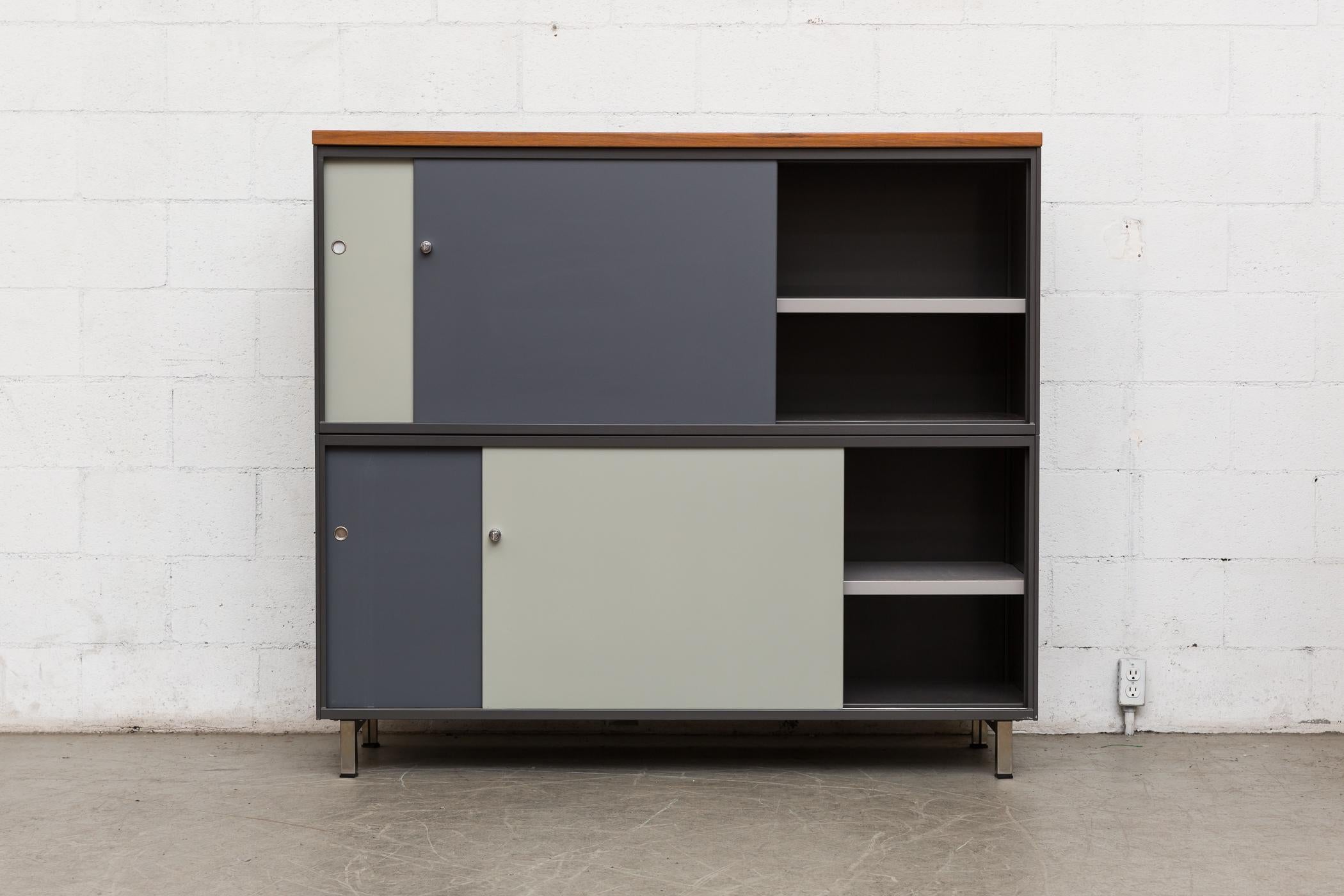 Extra large two-tier Gispen industrial metal cabinet designed with light and dark grey enameled metal doors and keyed locks. Movable shelves inside. Formica top with teak top. Original manufacturers tag. Very good original condition.