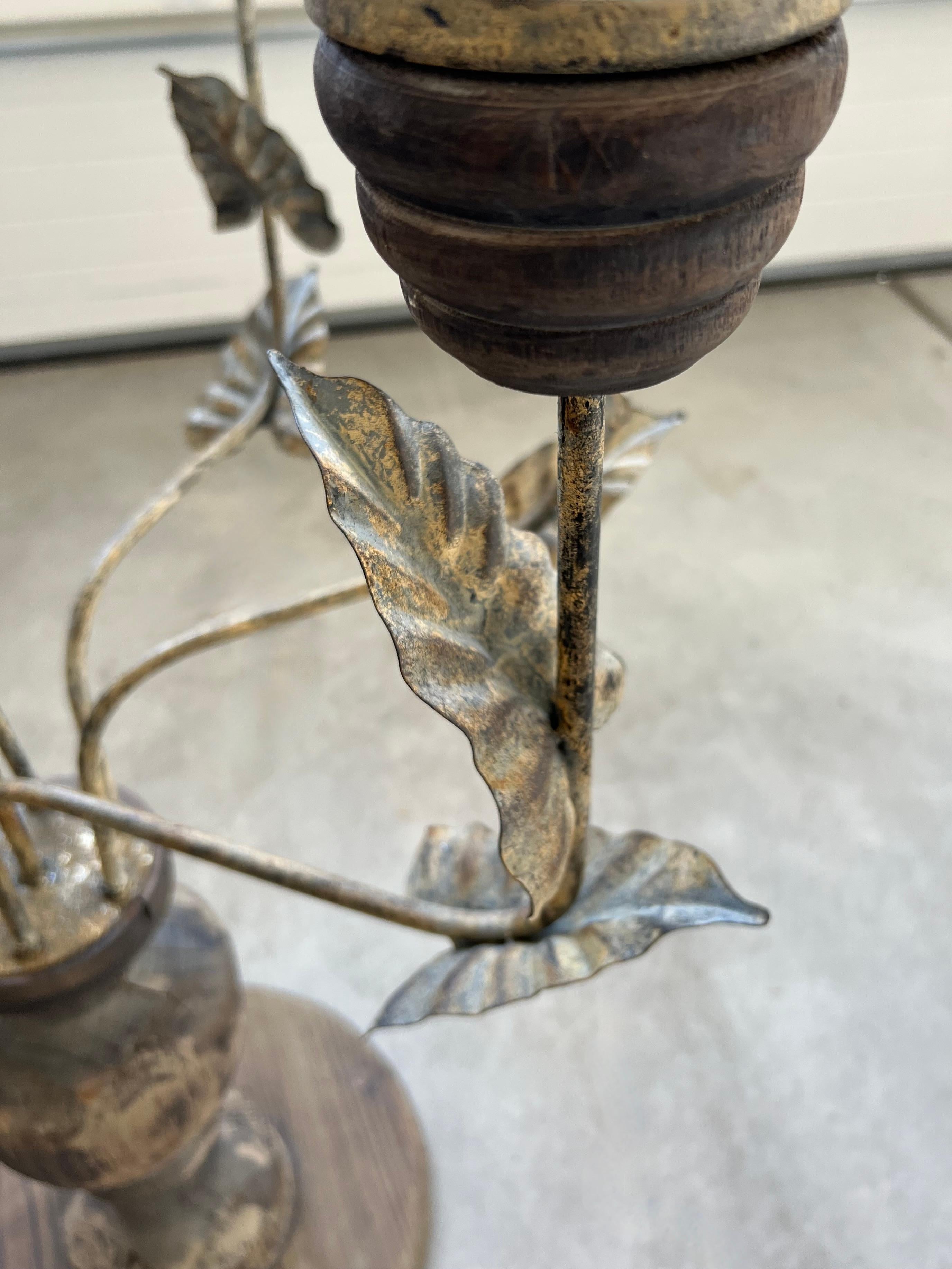 This giant candelabra holds seven pillar candles.  Six surround a candle holder that sits higher than the others in the middle. It has distressed painted metal arms and a sturdy rustic wood base.  The arms have metal foliage with distressed gilded