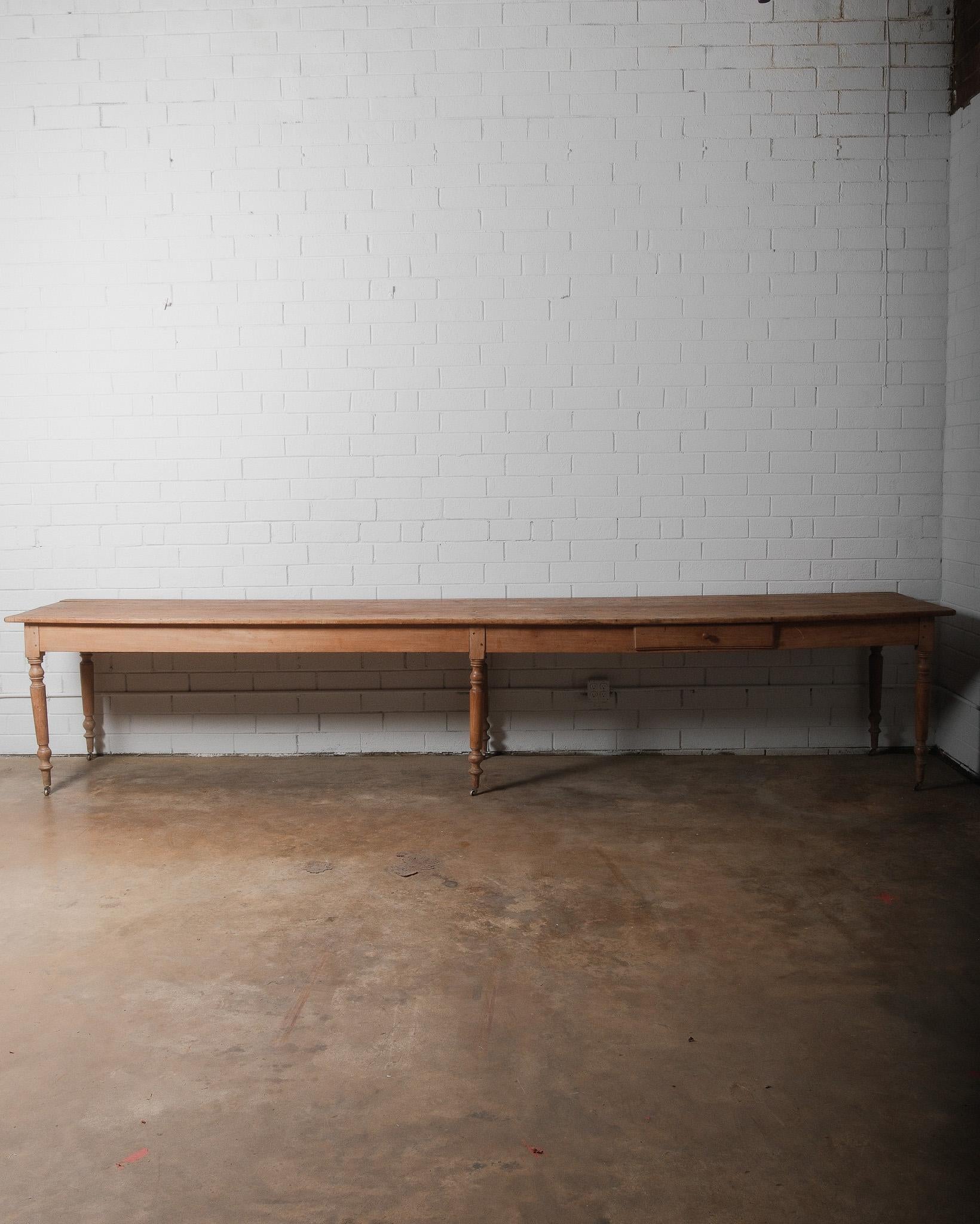This 19th-century French farmhouse table is an impressive piece, measuring over 12 feet long, making it an ideal dining table, worktable, or display piece. The solid pine plank top has developed a rich, timeworn patina, showing visible knots, grain