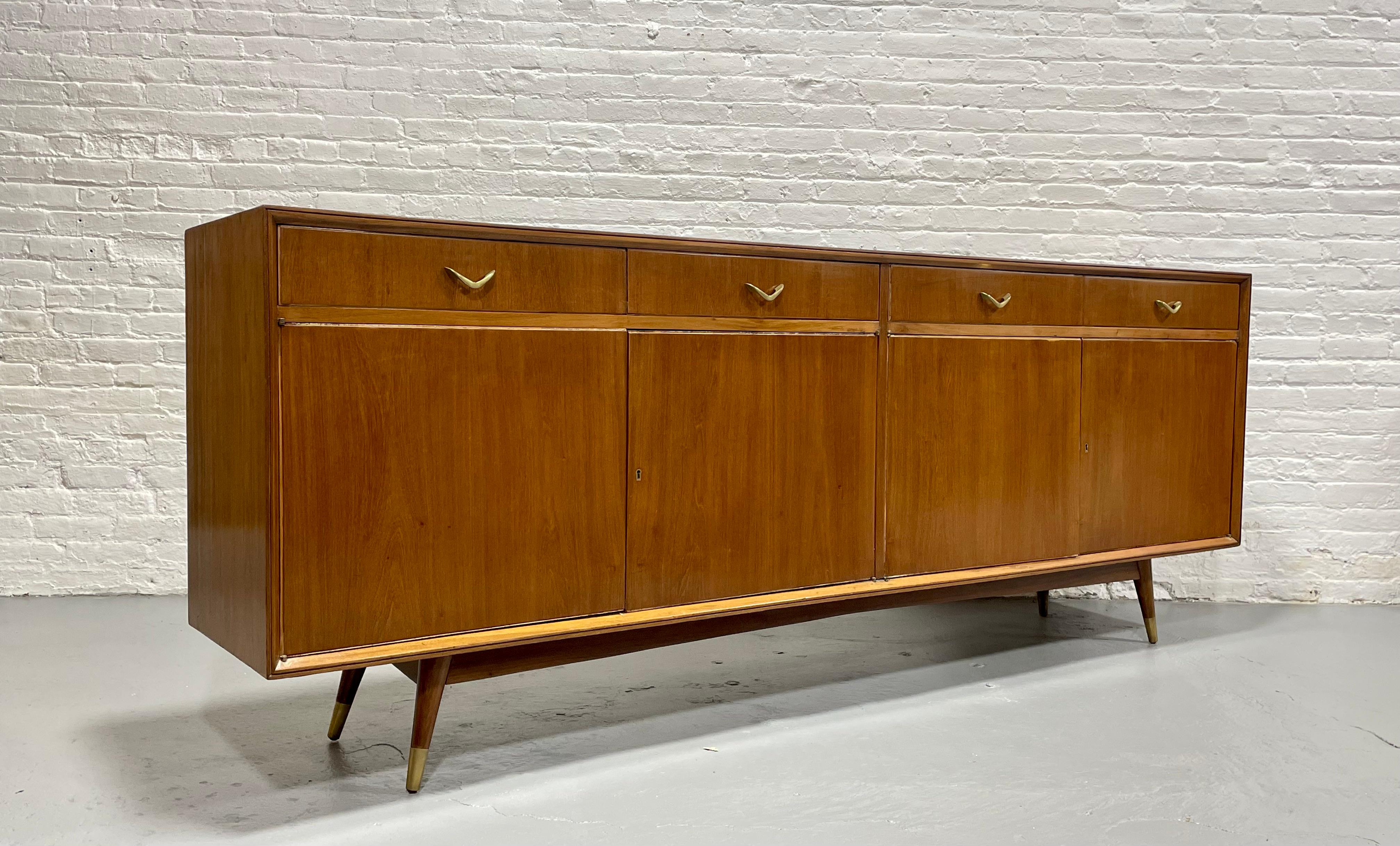 This EXTRA LONG Mid Century Modern credenza is an absolute showstopper in a hard to find length of over 8 feet. This tremendous piece boasts a rare example of French Mid Century Modern design.  Simple and classic design, brass capped legs and drawer