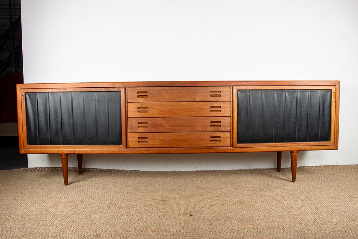 Eccezionale credenza scandinava molto, molto grande. Due grandi ante scorrevoli che si estendono per tutta la larghezza e sono rivestite in un elegante tessuto nero ondulato si aprono su due ampi ripiani regolabili in altezza e tre cassetti interni