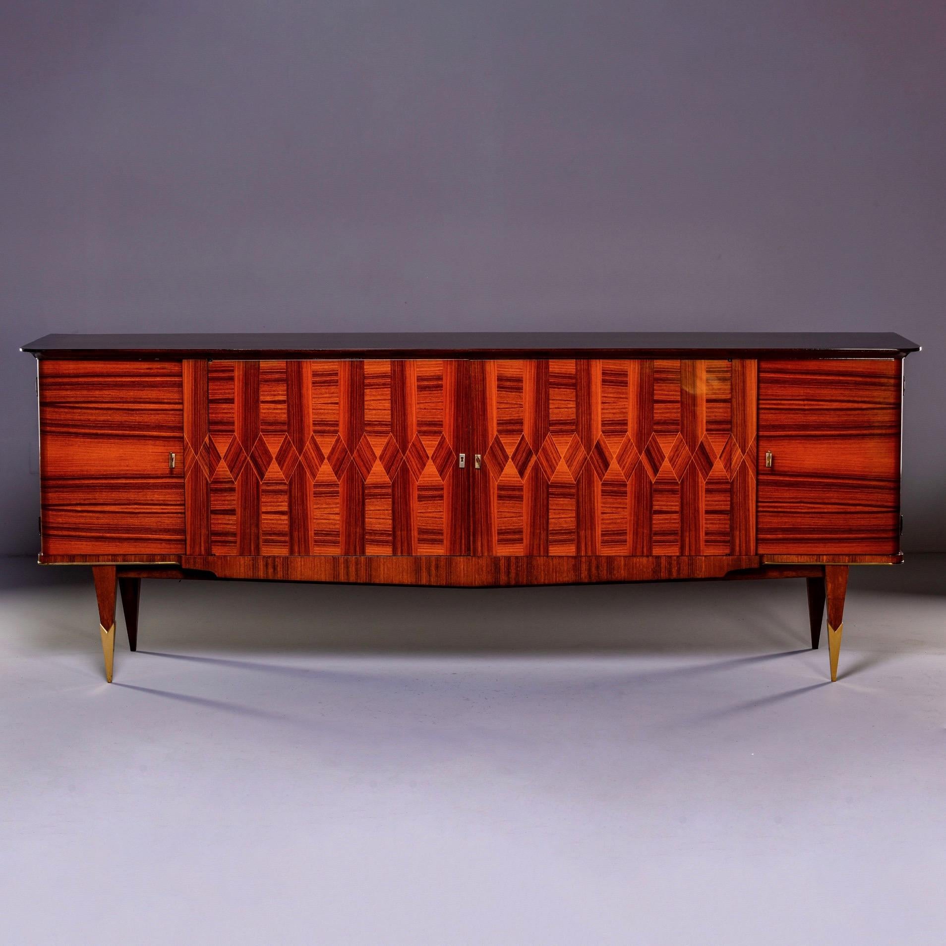 French extra large Art Deco buffet or credenza in Macassar, circa 1940s. Top of cabinet is ebonized wihile front features elaborate geometric marquetry. Locking cabinets on each end feature a top drawer with open storage below. The middle