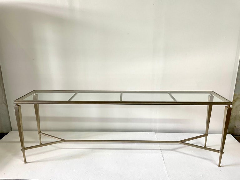This is an amazingly long and heavy gilded steel console table with a single piece of clear glass inset top.

Note: scuffs to legs and edges of top from normal use and wear. The glass is perfect with no scratches or chips.
