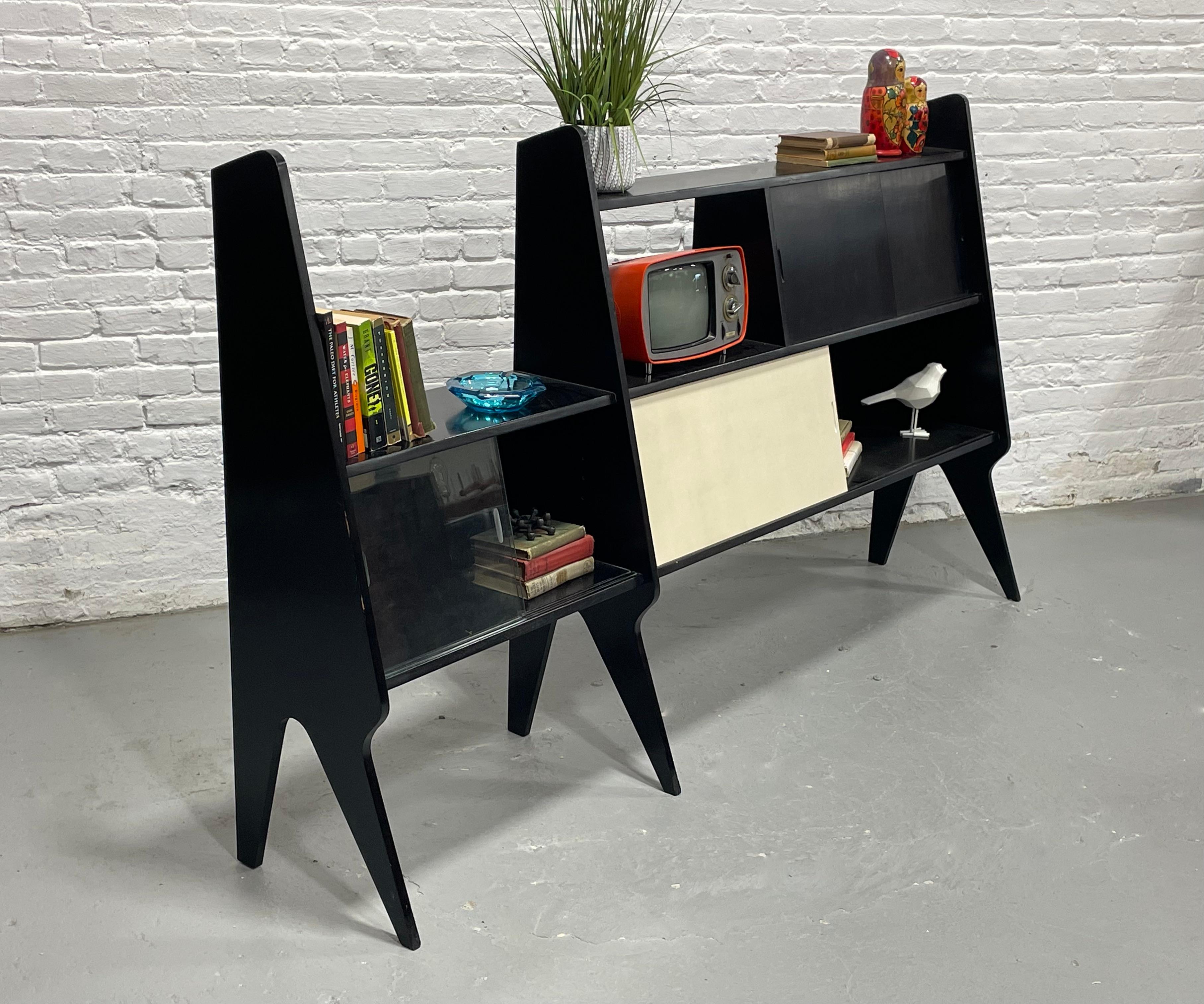 Striking and sculptural, this black lacquer wall unit is a one-of-a-kind statement piece. Designed with sleek angular legs inspired by Ponti, it offers ample storage for books, media, and decorative objects. A hidden bar cabinet adds an unexpected