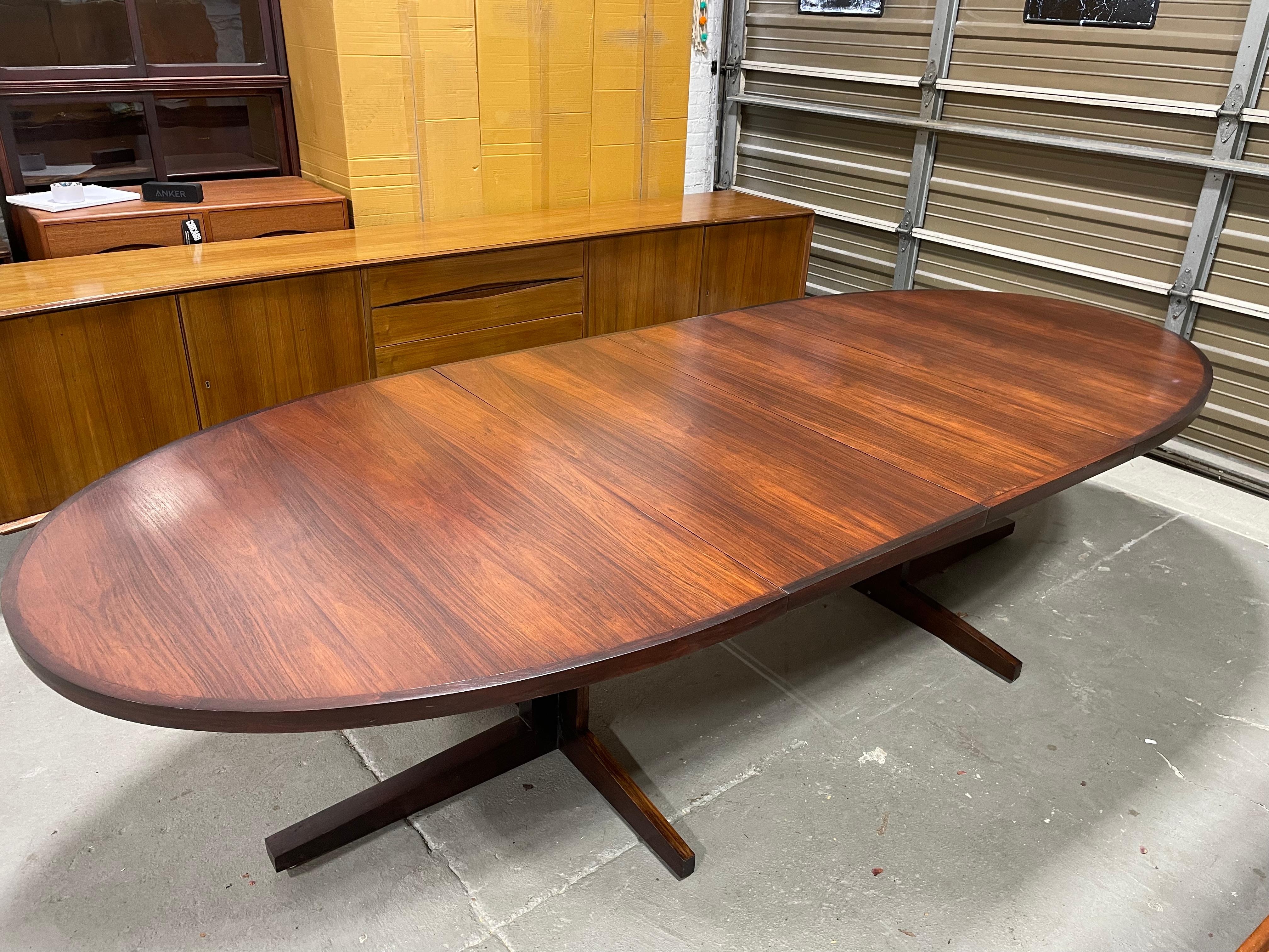 Extra Long Mid Century Modern Rosewood Oval Dining Table designed by John Mortensen for Heltborg Mobler, c. 1960’s.  The table has stunning wood grains across the tabletop and the pedestal legs are like none other, allowing for chairs to easily tuck