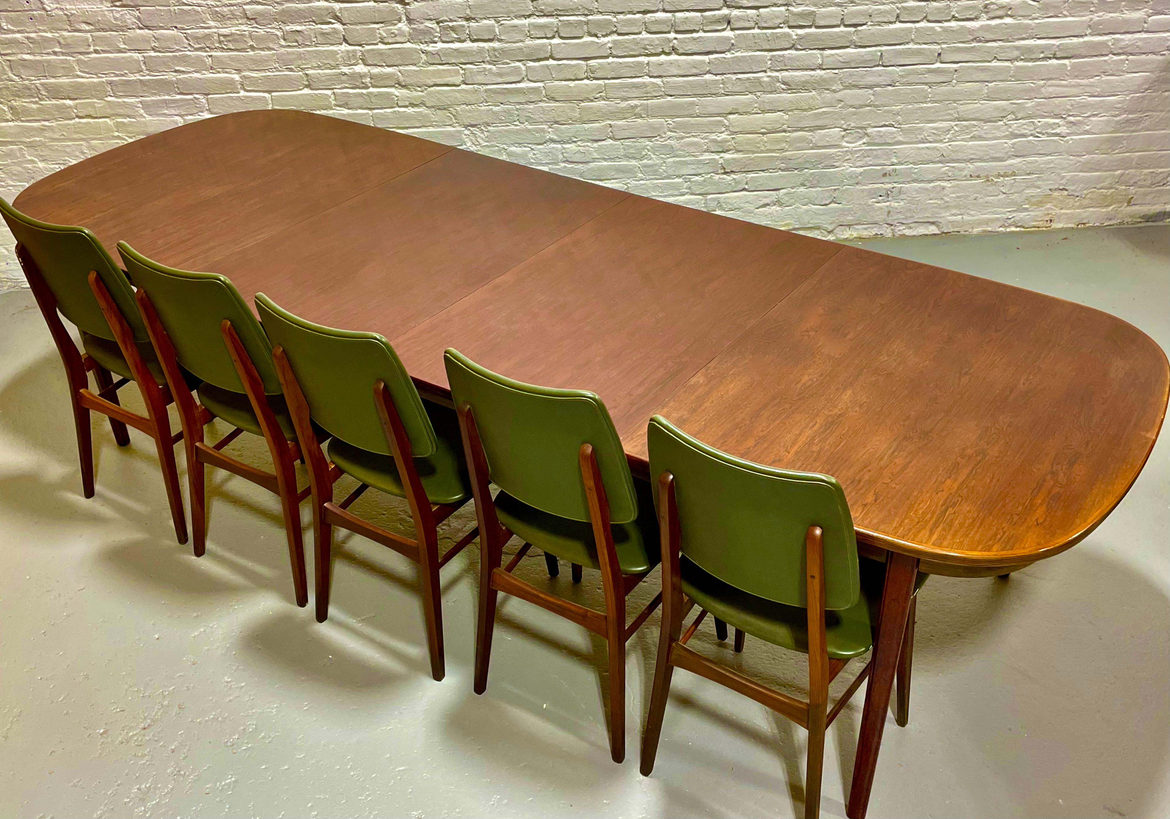 Extra Long Mid Century Modern Rosewood Oval-ish Dining Table, Made in Denmark, c. 1960’s.  The table expands to seat 12 guests - a truly rare find for those that love to entertain, but is compact in size without the leaves inserted and can