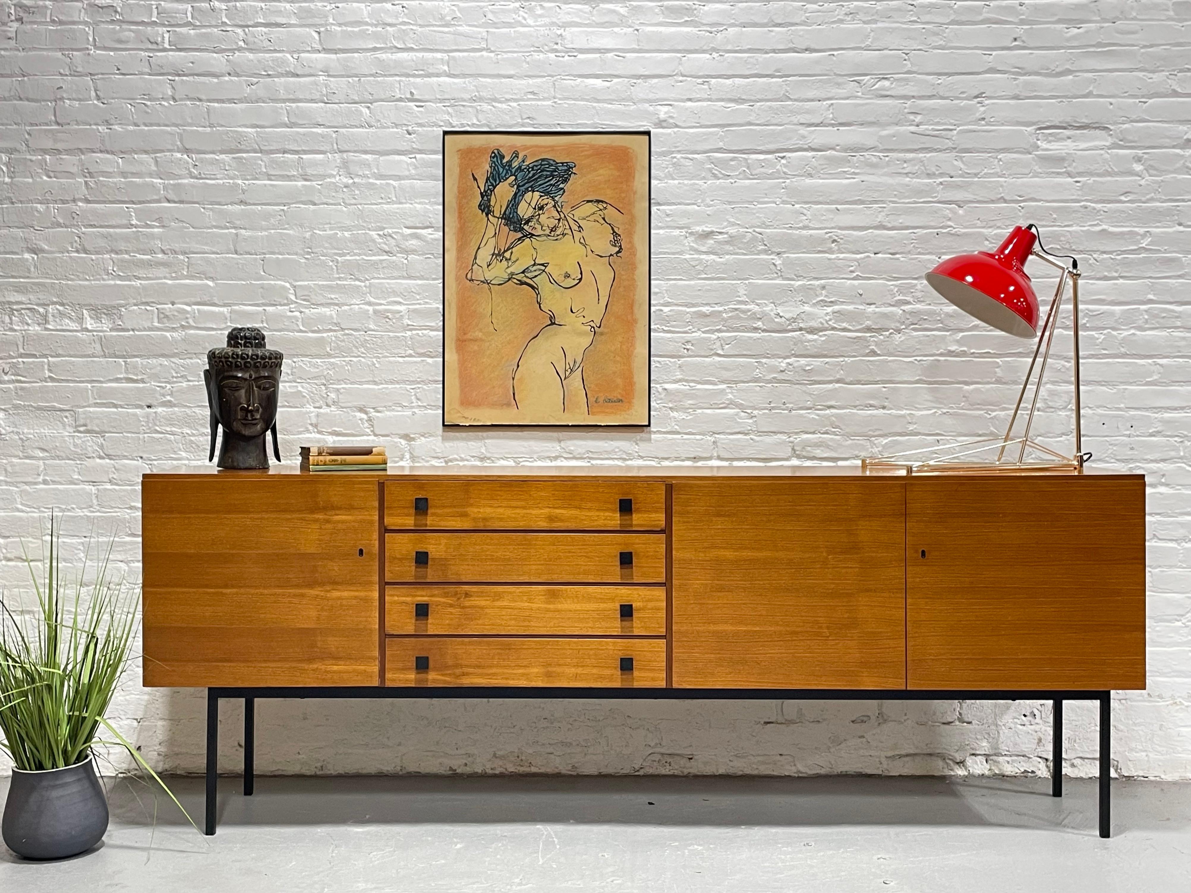 EXTRA LONG and just plain “EXTRA” in every sense. This Mid Century Modern Teak credenza, c. 1960s, is an absolute showstopper, boasting simple yet classic styling with ebonized hand pulls and base and lovely butterscotch coloring. Along with the