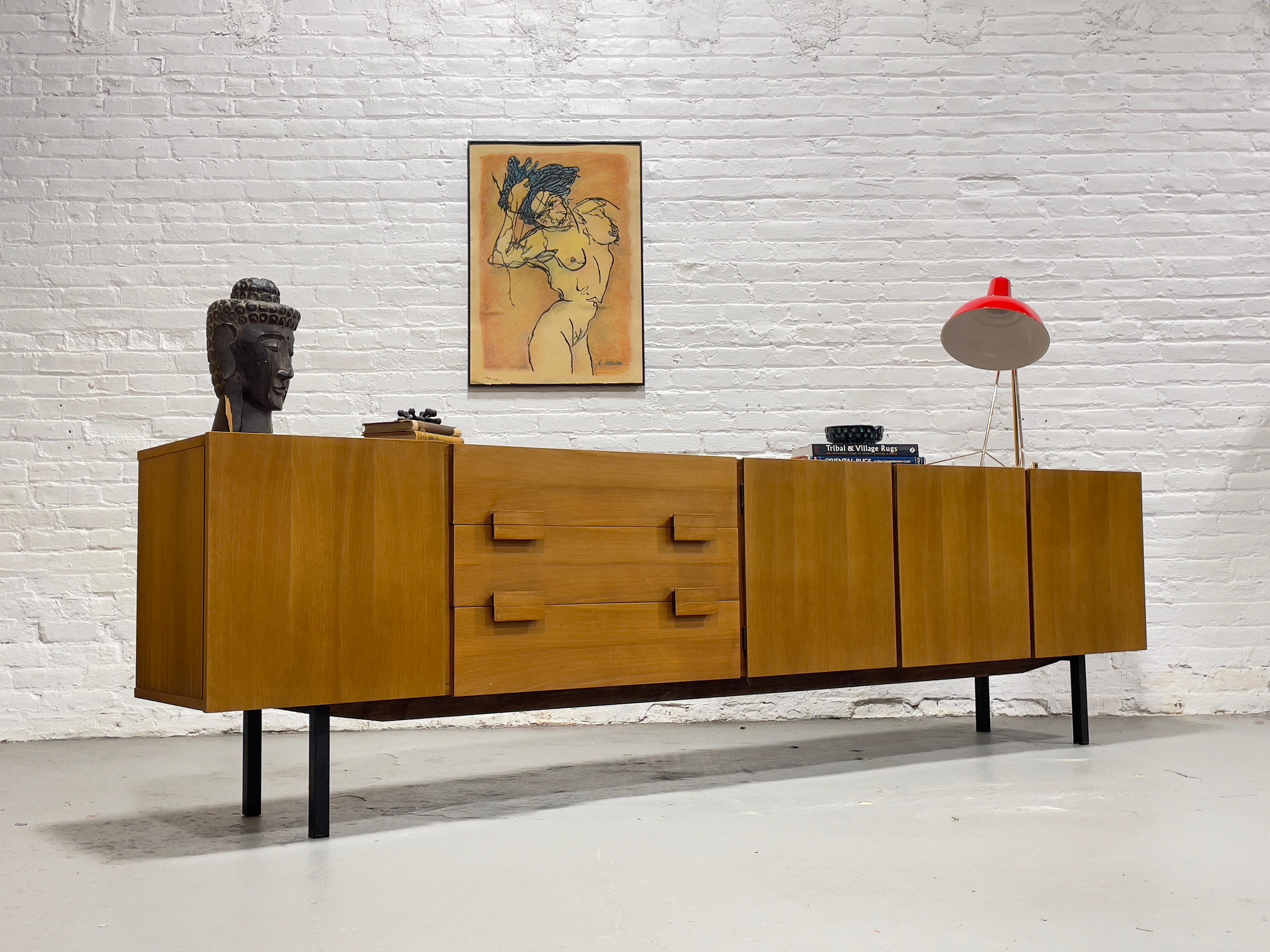 EXTRA LONG and just plain “EXTRA” in every sense. This Mid Century Modern Teak credenza, c. 1960s, is an absolute showstopper, boasting simple yet classic styling with chunky square hand pulls and solid ebonized metal legs. Along with the long size