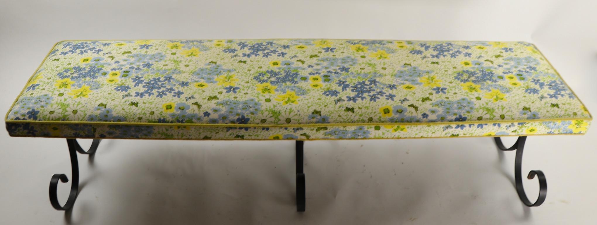 Stylish and fun bench with wrought iron curlicue legs and colorful floral pattern upholstered seat. Unusually long (67 inches) provides ample seating room. Original, clean ready to use condition.