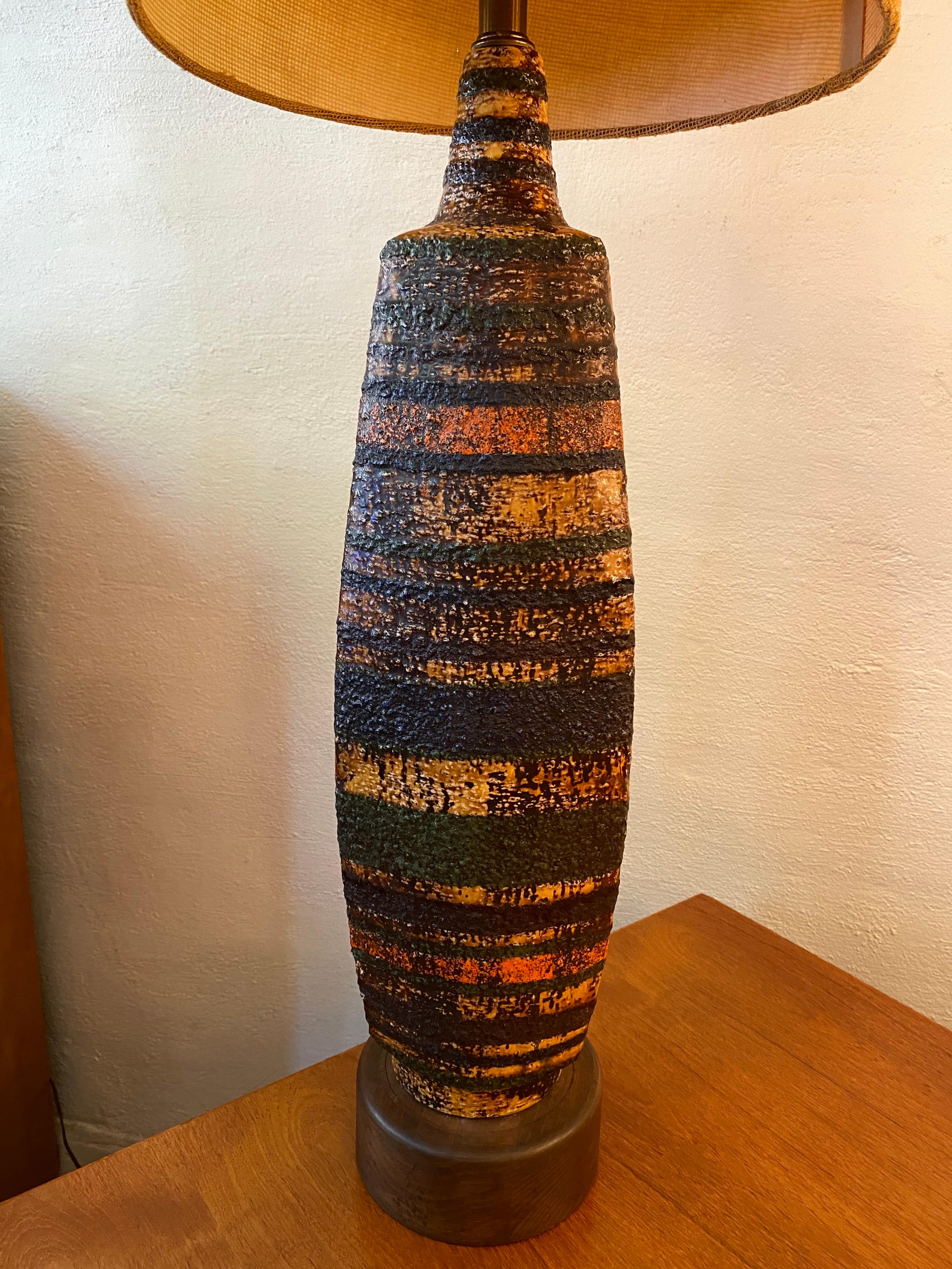 Extra tall ceramic table lamp with original burlap shade. Tall Ceramic body covered in shades of browns, golds and blacks. Lamp sits on a walnut base. Burlap shade is still very nice but shows typical wear. Lamp is probably from the late 1960's.