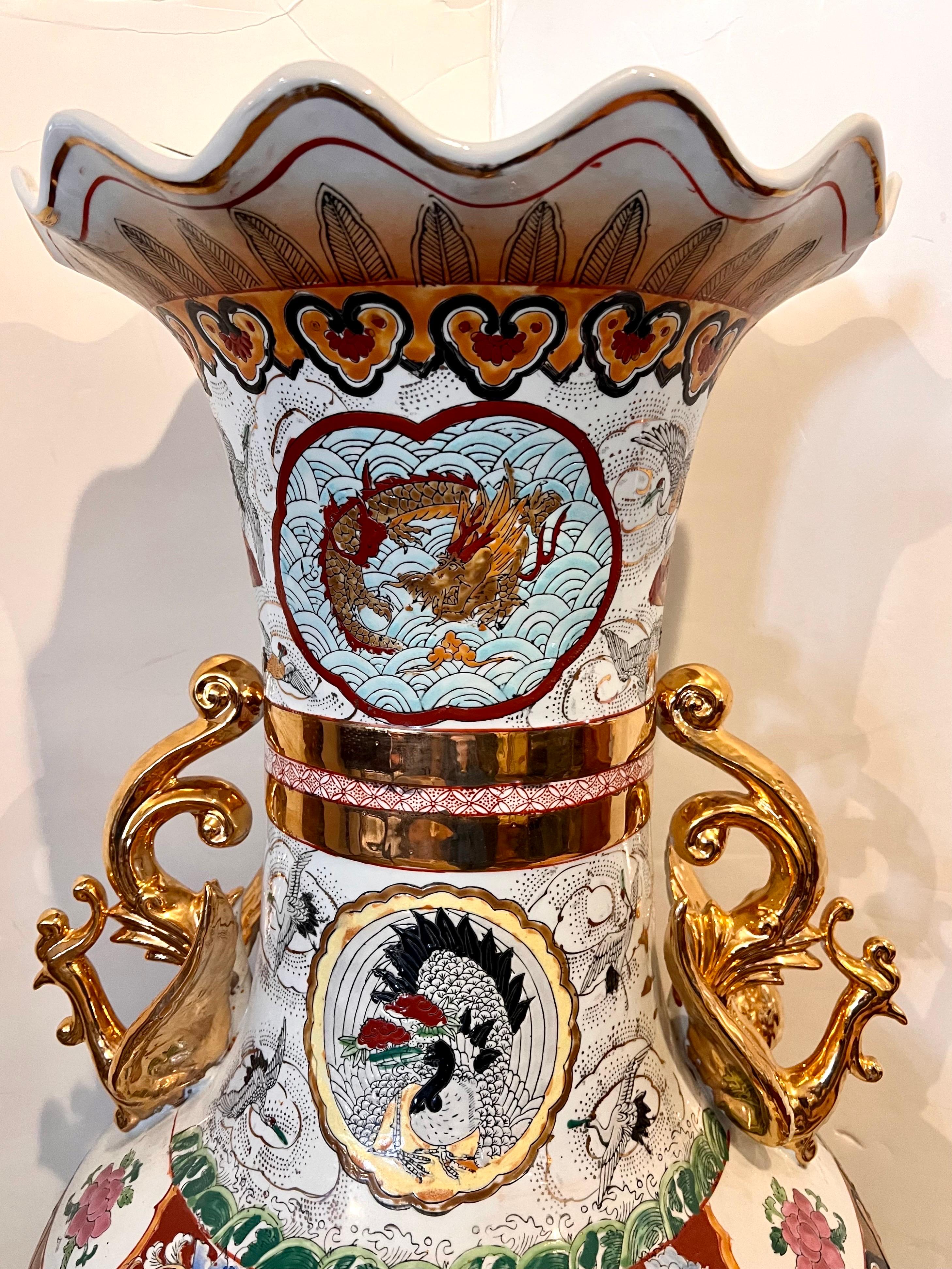 Extra large Chinese porcelain vase decorated with bright florals on a white ground with panels of colorful landscape scenery. The neck is decorated with applied gold phoenix birds underneath scalloped mouth rim. No hallmarks at bottom.