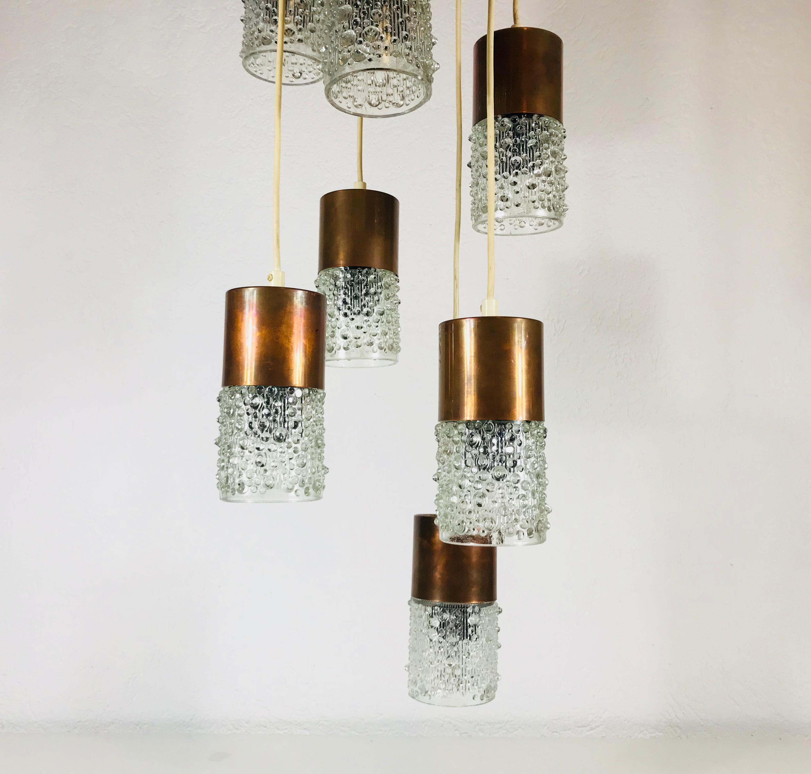 Cascade pendant lamp made in DDR in the 1960s. It is fascinating with its rare bubble glass shapes. The seven arms are all are made of polished copper and glas. The round top part above the lamp is bakelit and copper.

The light requires seven E14