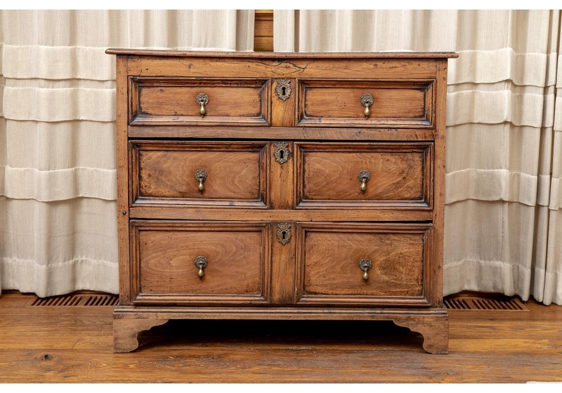 An important and striking Walnut Chest dating from the Early 18th Century with fine color and original hardware. The slightly overhanging top over three graduated long drawers that look like short ones, recessed with carved moldings. Each drawer