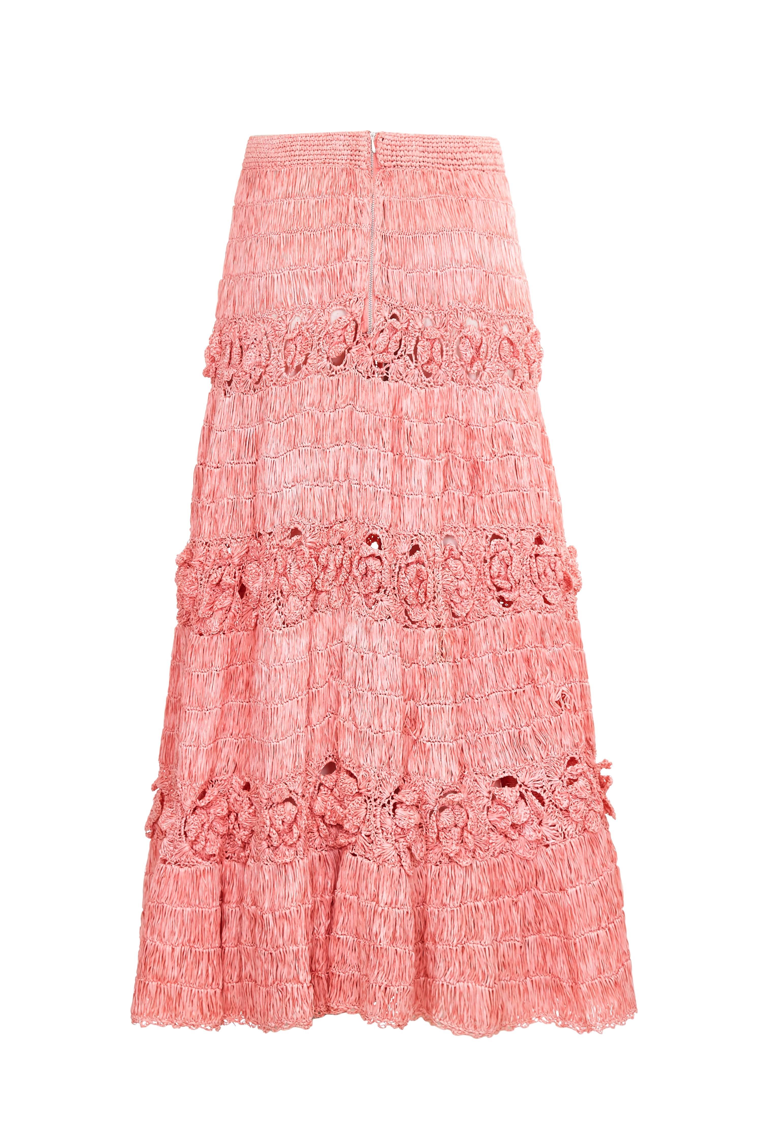 This extraordinary 1950s pale pink raffia skirt is a rare and extremely collectable piece. The intricate woven textile is interspersed with bands of detailed floral crochet work to create a tiered aesthetic and the textured fabric hangs beautifully
