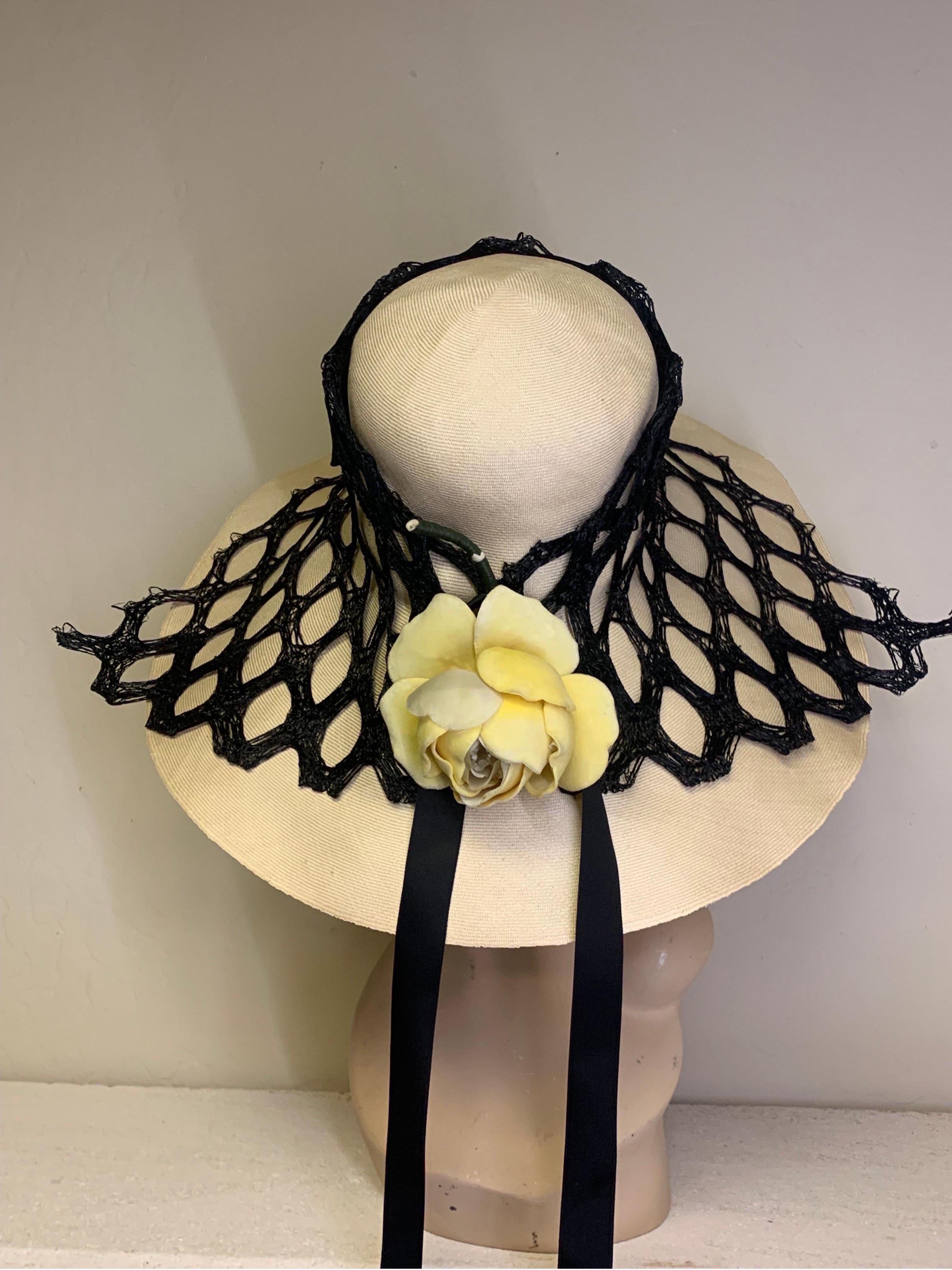 A striking 1960s Adolfo natural straw beach hat with extra wide brim and heavy veiling mesh drape with yellow silk rose accent. A silk satin ribbon is woven through top of mesh band and trails down back. Medium size. 