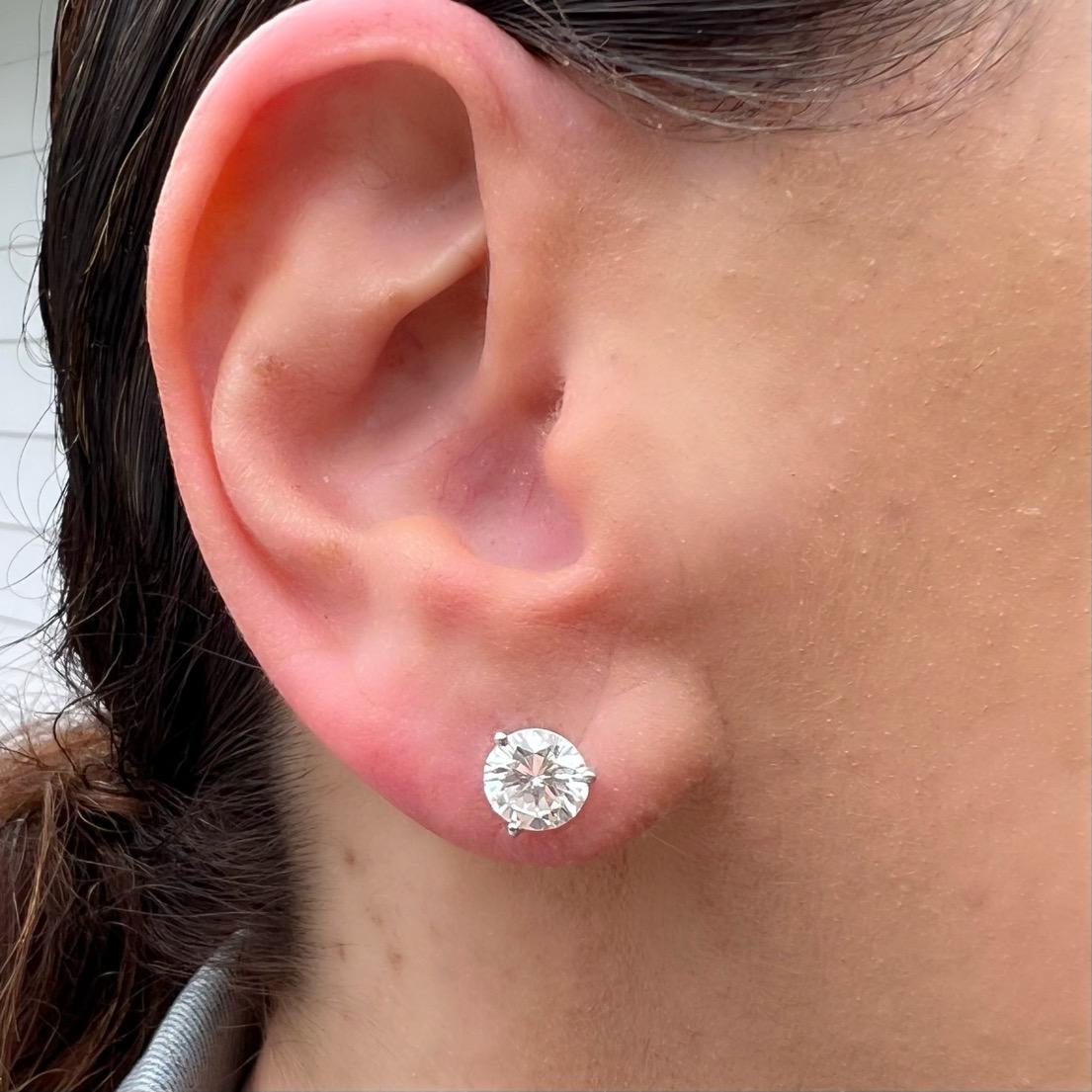 Diamond studs meant to be worn for a lifetime! These extremely white and clean round brilliant cut diamond studs feature two incredibly well matched diamonds weighing 1.57 carats and 1.55 carats, for a total diamond weight of 3.12 carats. Set in 18