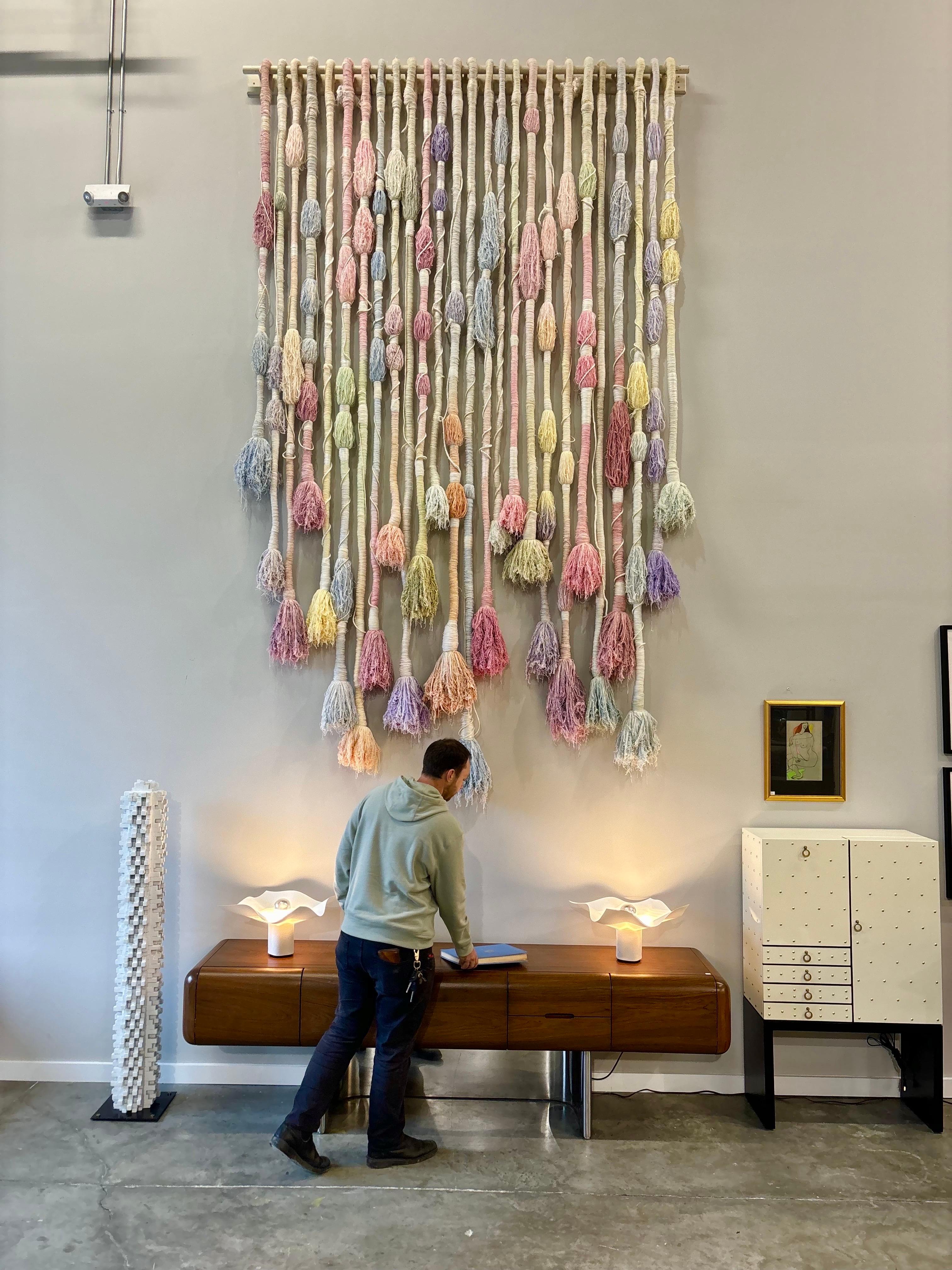 A truly incredible work of art.  This hanging sculpture is constructed of yarn-wrapped rope with incredible texture and color.  Each unique element hangs at different lengths and have different forms to their body.  
Mounted with a wood rod on wood