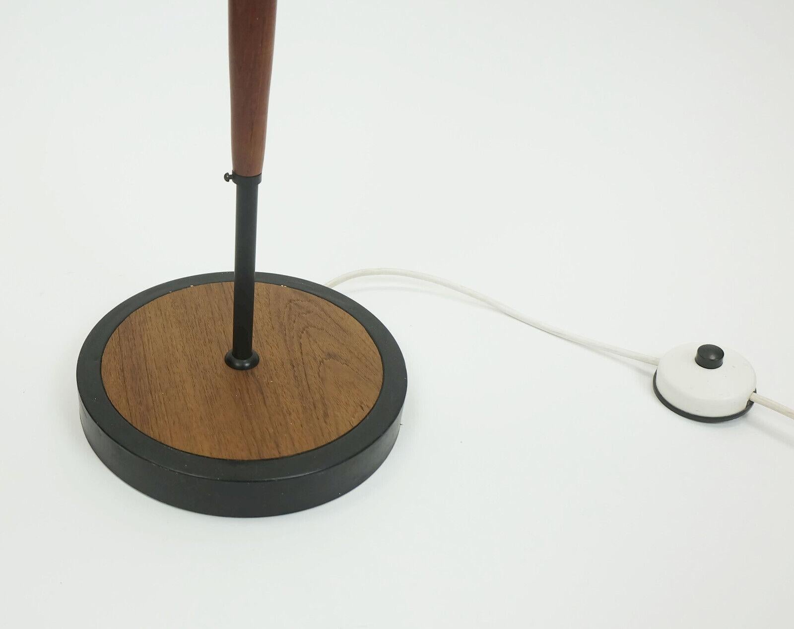 Lampada da terra molto insolita e rara dei primi anni '60. Struttura in metallo verniciato nero con elementi in legno di teak. Anche la base è dipinta di nero, mentre il piano è impiallacciato in teak. Il paralume è composto da due parti:
