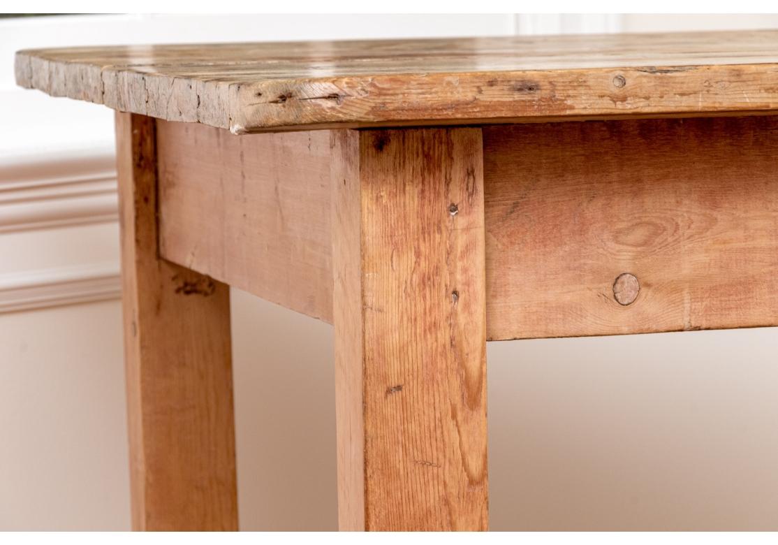 A remarkable six plank Antique Pine Table with great size, weight and stability. The finish is a soft stripped pine with intentional bits of the old finish remaining. On four thickly carved square form legs with rectangular table top and apron all