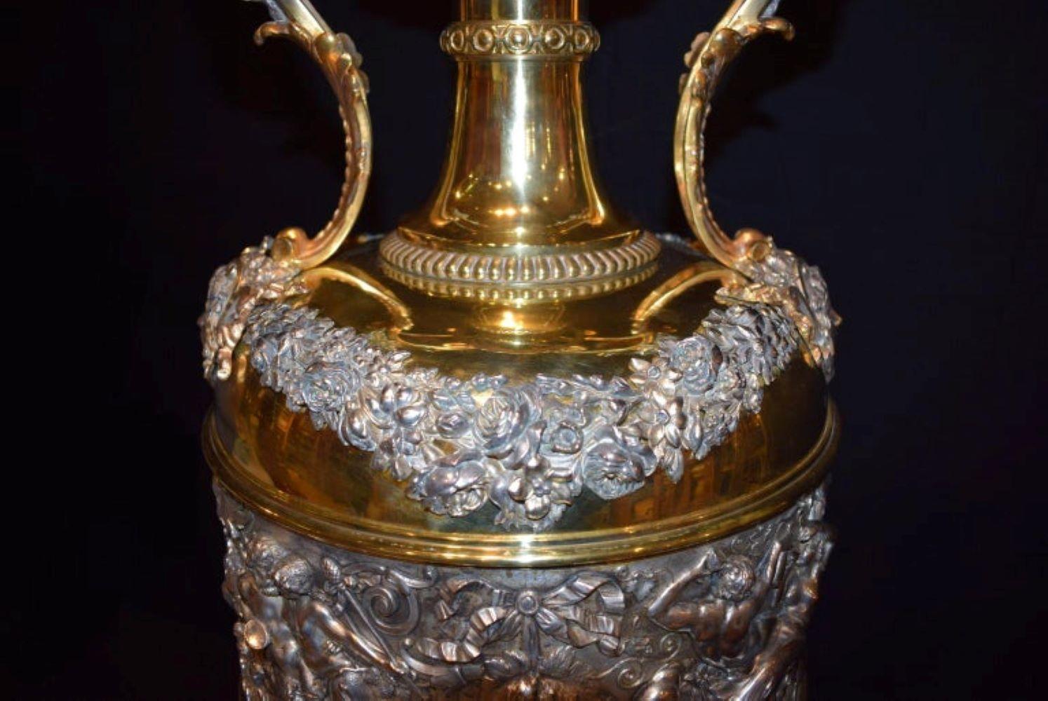 An Extraordinary large Belle Époque Urn in silver plate & gold plated with handles. An important Frieze Depicting Mythological figures ornate flower swags ending in female masks. At the bottom oval reserves and Lion's pelts over scroll. Dimensions: