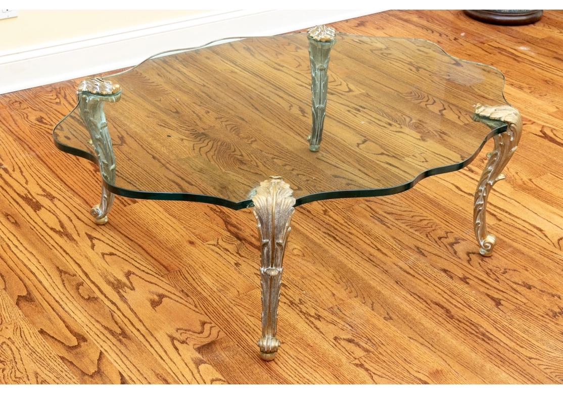 A very rare and exquisite Cocktail Table in Louis XVI Style. With a 1” thick beveled shaped glass top supported by four magnificently cast Gilt Bronze Acanthus form legs which feature a Snail’ Head foot.  Likely designed and created in France during