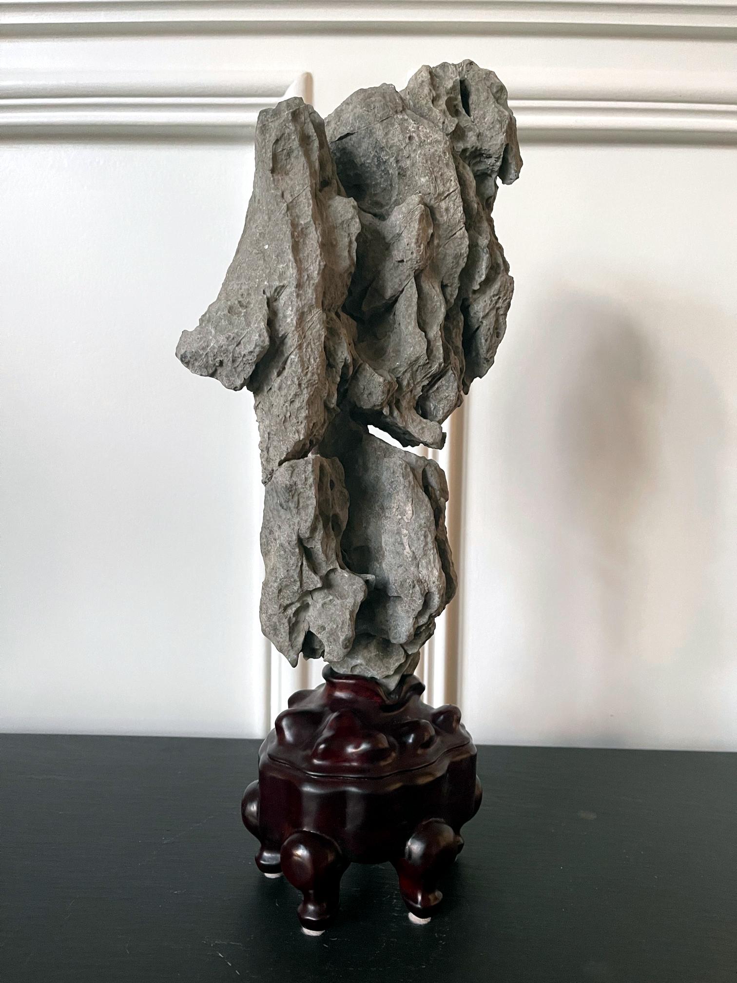 The Chinese scholar rock on offer here is a wonderful example of Yingde stone, a less common type than Lingbi or Taihu. Gray in color, it has an extraordinary upright form rising from a small stem, like an 