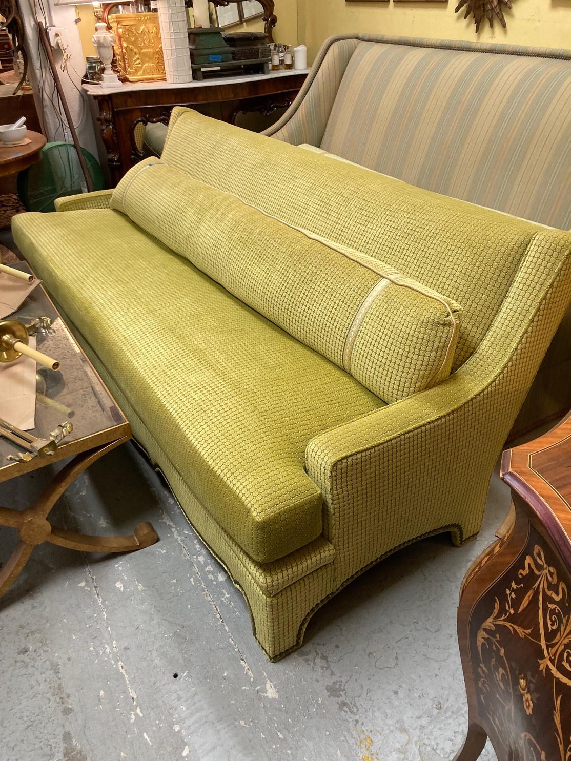 Striking and dramatic sofa with a sloping back, curved arms and interesting shaped seat rail with nail head trim. The elegant single long seat cushion in a down and feather mix. Upholstered in a Mid Century type cut velvet fabric in acid green in a