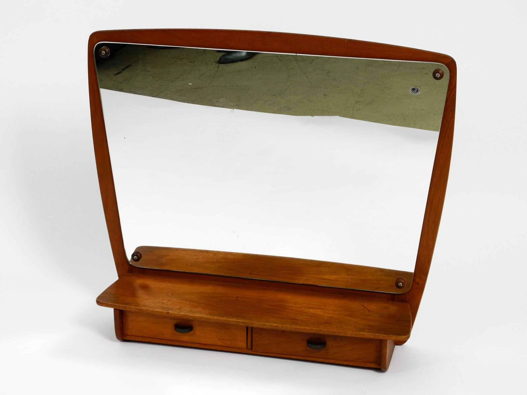 Extraordinary Danish mid century teak wall mirror with shelf and drawers. 
The thick original mirror glass is from the well-known glass manufacturer Carl Rotter from Lübeck.
With original label on the mirror.
Mirror is screwed to the teak frame