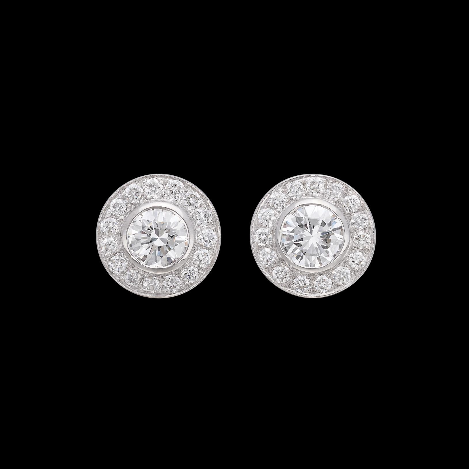 A knockout pair of earrings if ever there was one! A pair of exceptional GIA graded round brilliant cut diamonds are each expertly set in a halo of extremely fine melee diamonds for 2.99 carats. The well-matched center diamonds weigh a combined 2.06