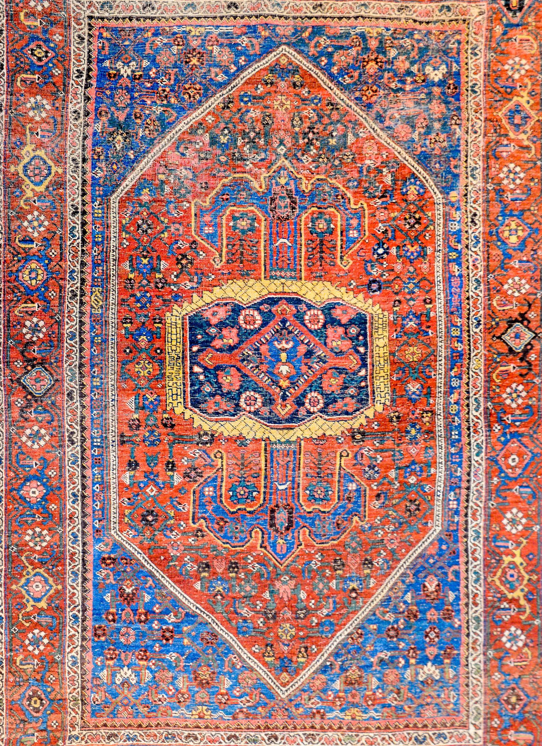 An extraordinary early 20th century Persian Bidjar with an intensely woven field of myriad flowers and scrolling vines woven in indigo, green, gold, white, and salmon colored vegetable dyed wool, on a bold crimson background. The border is equally