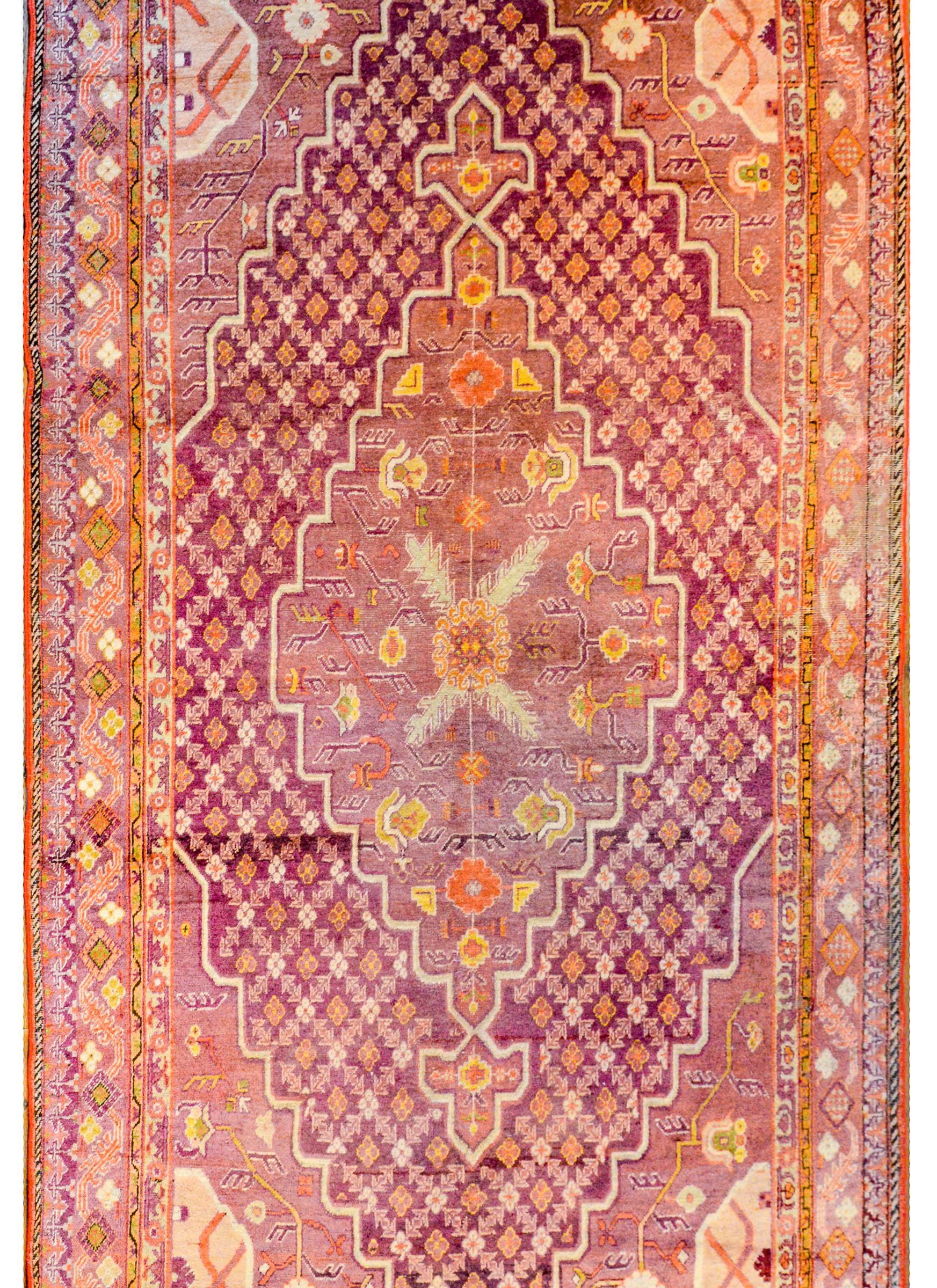 An extraordinary early 20th century Central Asian Khotan rug with a fantastic bold central medallion with a beautiful floral and vine pattern on a petite floral patterned ground, all woven in orange, gold, green, white, and violet. The border is
